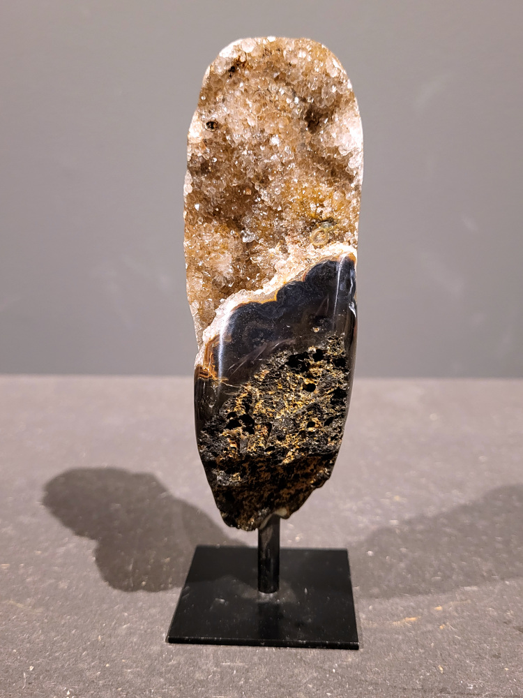 <strong>Agaat op standaard, 0,3kg, 15cm hoog, 17,- euro, nr. 46</strong>

<strong>Beschrijving Agaat.</strong>

Agaat is een veelzijdige edelsteen die bekend staat om zijn prachtige kleurbanden en patronen. Het is een variëteit van het mineraal kwarts, meer specifiek chalcedoon, en wordt vaak gebruikt in sieraden en als decoratieve steen. 
<strong>Algemene kenmerken:</strong>
Agaat is een microkristallijne vorm van kwarts, bestaande uit microscopisch kleine kristallen. 
<strong>Kleuren en patronen:</strong>
Agaat komt voor in vele kleuren, vaak met banden of lagen in verschillende tinten. 
Agaat is een populaire keuze voor het maken van kettingen, armbanden, ringen en andere sieraden vanwege de esthetische aantrekkingskracht en duurzaamheid. 
<strong>Spirituele eigenschappen:</strong>
Agaat wordt vaak geassocieerd met aardende, stabiliserende en beschermende eigenschappen. 
<strong>Helende werking:</strong>
Er wordt aangenomen dat agaat kan helpen bij het verminderen van stress, het bevorderen van emotioneel evenwicht en het versterken van het zelfvertrouwen. 
<strong>Verzorging van agaat:</strong>
Agaat is relatief gemakkelijk te onderhouden. Het kan worden gereinigd met lauw water, de rook van witte salie of palo santo, of door het op een hematiet- of bergkristal-cluster te plaatsen. 

<strong>-	Kunstgalerie-Arnold -</strong>