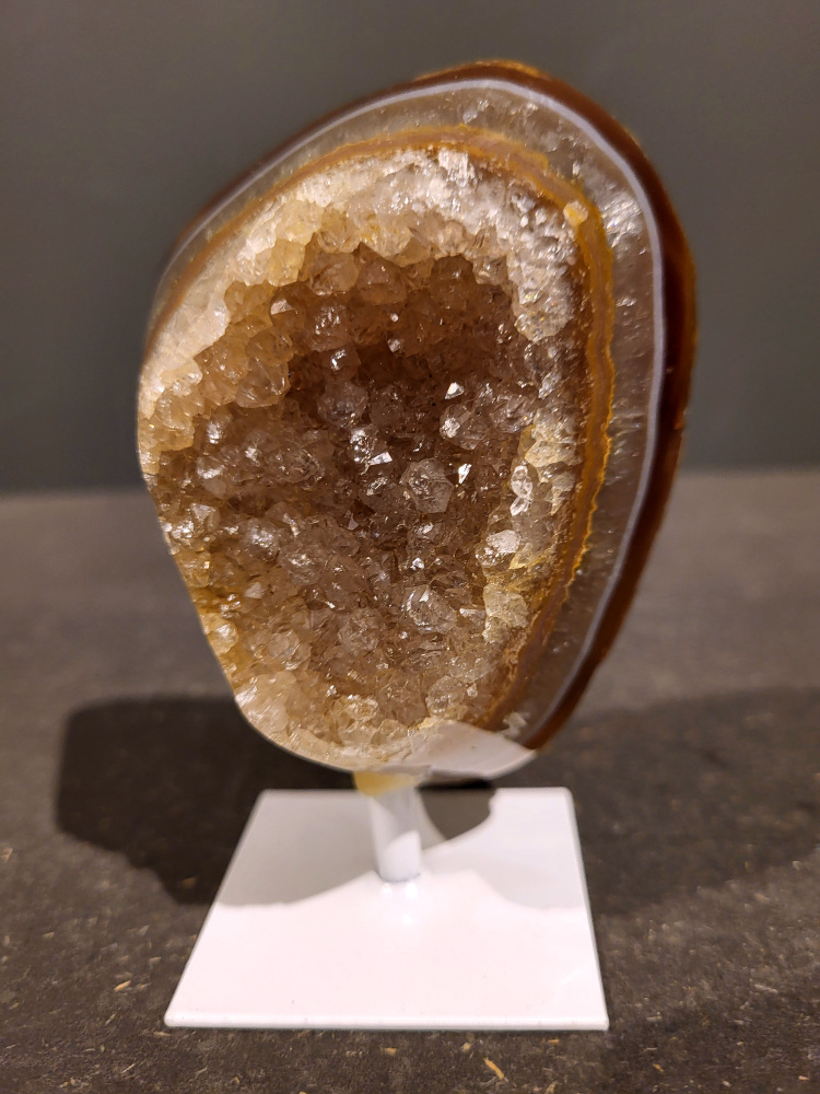 <strong>Agaat op standaard, 0,4kg, 11cm hoog, 19,- euro, nr. 44</strong>

<strong>Beschrijving Agaat.</strong>

Agaat is een veelzijdige edelsteen die bekend staat om zijn prachtige kleurbanden en patronen. Het is een variëteit van het mineraal kwarts, meer specifiek chalcedoon, en wordt vaak gebruikt in sieraden en als decoratieve steen. 
<strong>Algemene kenmerken:</strong>
Agaat is een microkristallijne vorm van kwarts, bestaande uit microscopisch kleine kristallen. 
<strong>Kleuren en patronen:</strong>
Agaat komt voor in vele kleuren, vaak met banden of lagen in verschillende tinten. 
Agaat is een populaire keuze voor het maken van kettingen, armbanden, ringen en andere sieraden vanwege de esthetische aantrekkingskracht en duurzaamheid. 
<strong>Spirituele eigenschappen:</strong>
Agaat wordt vaak geassocieerd met aardende, stabiliserende en beschermende eigenschappen. 
<strong>Helende werking:</strong>
Er wordt aangenomen dat agaat kan helpen bij het verminderen van stress, het bevorderen van emotioneel evenwicht en het versterken van het zelfvertrouwen. 
<strong>Verzorging van agaat:</strong>
Agaat is relatief gemakkelijk te onderhouden. Het kan worden gereinigd met lauw water, de rook van witte salie of palo santo, of door het op een hematiet- of bergkristal-cluster te plaatsen. 

<strong>-	Kunstgalerie-Arnold -
</strong>