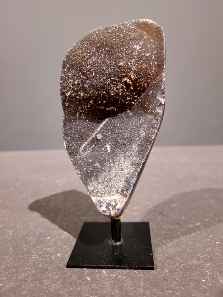 <strong>Agaat op standaard, 0,4kg, 14cm hoog, 20,- euro, nr. 43</strong>

<strong>Beschrijving Agaat.</strong>

Agaat is een veelzijdige edelsteen die bekend staat om zijn prachtige kleurbanden en patronen. Het is een variëteit van het mineraal kwarts, meer specifiek chalcedoon, en wordt vaak gebruikt in sieraden en als decoratieve steen. 
<strong>Algemene kenmerken:</strong>
Agaat is een microkristallijne vorm van kwarts, bestaande uit microscopisch kleine kristallen. 
<strong>Kleuren en patronen:</strong>
Agaat komt voor in vele kleuren, vaak met banden of lagen in verschillende tinten. 
Agaat is een populaire keuze voor het maken van kettingen, armbanden, ringen en andere sieraden vanwege de esthetische aantrekkingskracht en duurzaamheid. 
<strong>Spirituele eigenschappen:</strong>
Agaat wordt vaak geassocieerd met aardende, stabiliserende en beschermende eigenschappen. 
<strong>Helende werking:</strong>
Er wordt aangenomen dat agaat kan helpen bij het verminderen van stress, het bevorderen van emotioneel evenwicht en het versterken van het zelfvertrouwen. 
<strong>Verzorging van agaat:</strong>
Agaat is relatief gemakkelijk te onderhouden. Het kan worden gereinigd met lauw water, de rook van witte salie of palo santo, of door het op een hematiet- of bergkristal-cluster te plaatsen. 

<strong>-	Kunstgalerie-Arnold -</strong>