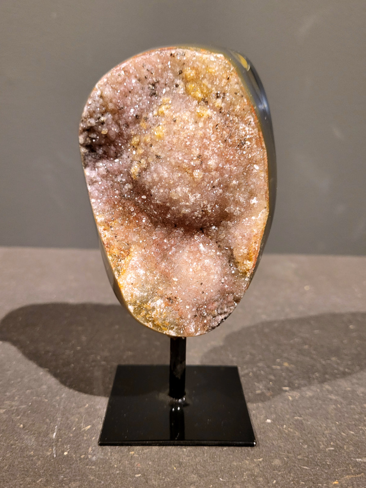 <strong>Agaat op standaard, 0,5kg, 14cm hoog, 27,- euro, nr. 7</strong>

<strong>Beschrijving Agaat.</strong>

Agaat is een veelzijdige edelsteen die bekend staat om zijn prachtige kleurbanden en patronen. Het is een variëteit van het mineraal kwarts, meer specifiek chalcedoon, en wordt vaak gebruikt in sieraden en als decoratieve steen. 
<strong>Algemene kenmerken:</strong>
Agaat is een microkristallijne vorm van kwarts, bestaande uit microscopisch kleine kristallen. 
<strong>Kleuren en patronen:</strong>
Agaat komt voor in vele kleuren, vaak met banden of lagen in verschillende tinten. 
Agaat is een populaire keuze voor het maken van kettingen, armbanden, ringen en andere sieraden vanwege de esthetische aantrekkingskracht en duurzaamheid. 
<strong>Spirituele eigenschappen:</strong>
Agaat wordt vaak geassocieerd met aardende, stabiliserende en beschermende eigenschappen. 
<strong>Helende werking:</strong>
Er wordt aangenomen dat agaat kan helpen bij het verminderen van stress, het bevorderen van emotioneel evenwicht en het versterken van het zelfvertrouwen. 
<strong>Verzorging van agaat:</strong>
Agaat is relatief gemakkelijk te onderhouden. Het kan worden gereinigd met lauw water, de rook van witte salie of palo santo, of door het op een hematiet- of bergkristal-cluster te plaatsen. 

<strong>-	Kunstgalerie-Arnold -</strong>