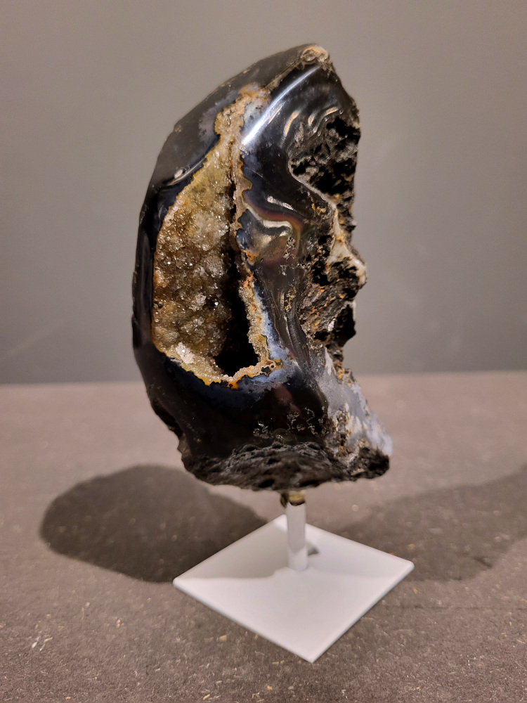 <strong>Agaat op standaard, 0,5kg, 16cm hoog, 25,- euro, nr. 36</strong>

<strong>Beschrijving Agaat.</strong>

Agaat is een veelzijdige edelsteen die bekend staat om zijn prachtige kleurbanden en patronen. Het is een variëteit van het mineraal kwarts, meer specifiek chalcedoon, en wordt vaak gebruikt in sieraden en als decoratieve steen. 
<strong>Algemene kenmerken:</strong>
Agaat is een microkristallijne vorm van kwarts, bestaande uit microscopisch kleine kristallen. 
<strong>Kleuren en patronen:</strong>
Agaat komt voor in vele kleuren, vaak met banden of lagen in verschillende tinten. 
Agaat is een populaire keuze voor het maken van kettingen, armbanden, ringen en andere sieraden vanwege de esthetische aantrekkingskracht en duurzaamheid. 
<strong>Spirituele eigenschappen:</strong>
Agaat wordt vaak geassocieerd met aardende, stabiliserende en beschermende eigenschappen. 
<strong>Helende werking:</strong>
Er wordt aangenomen dat agaat kan helpen bij het verminderen van stress, het bevorderen van emotioneel evenwicht en het versterken van het zelfvertrouwen. 
<strong>Verzorging van agaat:</strong>
Agaat is relatief gemakkelijk te onderhouden. Het kan worden gereinigd met lauw water, de rook van witte salie of palo santo, of door het op een hematiet- of bergkristal-cluster te plaatsen. 

<strong>-	Kunstgalerie-Arnold -</strong>