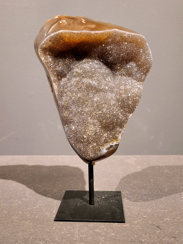 <strong>Agaat op standaard, 1,6kg, 23cm hoog, 80,- euro, nr. 28</strong>

<strong>Beschrijving Agaat.</strong>

Agaat is een veelzijdige edelsteen die bekend staat om zijn prachtige kleurbanden en patronen. Het is een variëteit van het mineraal kwarts, meer specifiek chalcedoon, en wordt vaak gebruikt in sieraden en als decoratieve steen. 
<strong>Algemene kenmerken:</strong>
Agaat is een microkristallijne vorm van kwarts, bestaande uit microscopisch kleine kristallen. 
<strong>Kleuren en patronen:</strong>
Agaat komt voor in vele kleuren, vaak met banden of lagen in verschillende tinten. 
Agaat is een populaire keuze voor het maken van kettingen, armbanden, ringen en andere sieraden vanwege de esthetische aantrekkingskracht en duurzaamheid. 
<strong>Spirituele eigenschappen:</strong>
Agaat wordt vaak geassocieerd met aardende, stabiliserende en beschermende eigenschappen. 
<strong>Helende werking:</strong>
Er wordt aangenomen dat agaat kan helpen bij het verminderen van stress, het bevorderen van emotioneel evenwicht en het versterken van het zelfvertrouwen. 
<strong>Verzorging van agaat:</strong>
Agaat is relatief gemakkelijk te onderhouden. Het kan worden gereinigd met lauw water, de rook van witte salie of palo santo, of door het op een hematiet- of bergkristal-cluster te plaatsen. 

<strong>-	Kunstgalerie-Arnold -</strong>