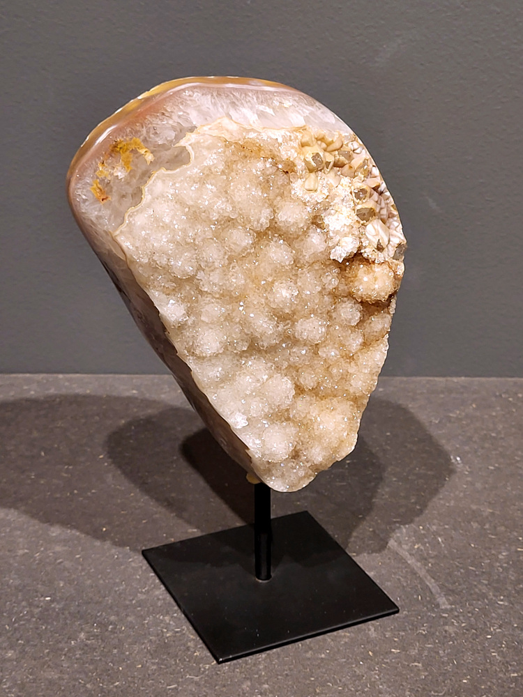 <strong>Agaat op standaard, 20cm hoog, 1,6 kg, 78,- euro, nr. 19</strong>

Agaat is een veelzijdige edelsteen die bekend staat om zijn prachtige kleurbanden en patronen. Het is een variëteit van het mineraal kwarts, meer specifiek chalcedoon, en wordt vaak gebruikt in sieraden en als decoratieve steen. 
<strong>Algemene kenmerken:</strong>
Agaat is een microkristallijne vorm van kwarts, bestaande uit microscopisch kleine kristallen. 
<strong>Kleuren en patronen:</strong>
Agaat komt voor in vele kleuren, vaak met banden of lagen in verschillende tinten. 
Agaat is een populaire keuze voor het maken van kettingen, armbanden, ringen en andere sieraden vanwege de esthetische aantrekkingskracht en duurzaamheid. 
<strong>Spirituele eigenschappen:</strong>
Agaat wordt vaak geassocieerd met aardende, stabiliserende en beschermende eigenschappen. 
<strong>Helende werking:</strong>
Er wordt aangenomen dat agaat kan helpen bij het verminderen van stress, het bevorderen van emotioneel evenwicht en het versterken van het zelfvertrouwen. 
<strong>Verzorging van agaat:</strong>
Agaat is relatief gemakkelijk te onderhouden. Het kan worden gereinigd met lauw water, de rook van witte salie of palo santo, of door het op een hematiet- of bergkristal-cluster te plaatsen. 

<strong>-	Kunstgalerie-Arnold -</strong>