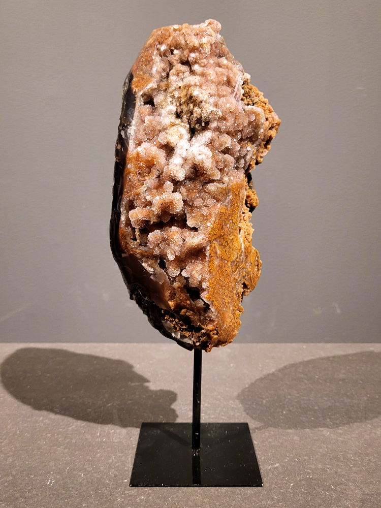 <strong>Agaat op standaard, 3,3kg, 32cm hoog, 166,- euro, nr. 26</strong>

<strong>Beschrijving Agaat.</strong>

Agaat is een veelzijdige edelsteen die bekend staat om zijn prachtige kleurbanden en patronen. Het is een variëteit van het mineraal kwarts, meer specifiek chalcedoon, en wordt vaak gebruikt in sieraden en als decoratieve steen. 
<strong>Algemene kenmerken:</strong>
Agaat is een microkristallijne vorm van kwarts, bestaande uit microscopisch kleine kristallen. 
<strong>Kleuren en patronen:</strong>
Agaat komt voor in vele kleuren, vaak met banden of lagen in verschillende tinten. 
Agaat is een populaire keuze voor het maken van kettingen, armbanden, ringen en andere sieraden vanwege de esthetische aantrekkingskracht en duurzaamheid. 
<strong>Spirituele eigenschappen:</strong>
Agaat wordt vaak geassocieerd met aardende, stabiliserende en beschermende eigenschappen. 
<strong>Helende werking:</strong>
Er wordt aangenomen dat agaat kan helpen bij het verminderen van stress, het bevorderen van emotioneel evenwicht en het versterken van het zelfvertrouwen. 
<strong>Verzorging van agaat:</strong>
Agaat is relatief gemakkelijk te onderhouden. Het kan worden gereinigd met lauw water, de rook van witte salie of palo santo, of door het op een hematiet- of bergkristal-cluster te plaatsen. 

<strong>-	Kunstgalerie-Arnold -</strong>