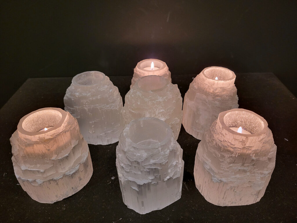 Seleniet, Waxine lichten, 11cm hoog, doorsnee 9 cm, 10,- euro, nr. 3

Seleniet is een vorm van gips, een mineraal met een vezelige structuur. Het staat bekend om zijn heldere, witte kleur en wordt vaak "satijnspaat" genoemd vanwege zijn glans. Seleniet kan ook andere kleuren hebben, zoals geel, oranje en rood. De naam "seleniet" komt van de Griekse maangodin Selene, vanwege de maanachtige glans van de steen. 
Eigenschappen en kenmerken:
Kleur: Meestal wit, maar kan ook geel, oranje, rood, groen of blauw zijn. 
Vorm: Vaak in lange, dunne kristallen, soms ook als woestijnrozen. 
Textuur: Vezelig en glanzend, met een satijnachtige uitstraling. 
Hardheid: 2 op de schaal van Mohs, wat betekent dat het zacht is en makkelijk kan krassen. 
Vorming: Ontstaat door de verdamping van zoutwatermeren en -zeeën. 
Spirituele en helende eigenschappen:
Seleniet wordt vaak gebruikt in spirituele praktijken en meditatie, vanwege de vermeende kalmerende en reinigende werking. 
Het wordt vaak geassocieerd met het reinigen en opladen van andere edelstenen. 
Seleniet zou helpen om negatieve energie te verwijderen, helderheid van geest te bevorderen en contact te maken met hogere bewustzijnsniveaus. 
In de edelsteentherapie wordt seleniet gebruikt voor ontspanning en het loslaten van spanningen. 
Toepassingen:
Decoratieve doeleinden, zoals beeldjes en lampen.
Spirituele doeleinden, zoals meditatie en healing.
Sieraden.
Het maken van raampjes (Mariaglas). 
Belangrijk: Seleniet is gevoelig voor water en kan oplossen of beschadigen als het te lang met water in aanraking komt. 
Andere namen:
Satijnspaat, Mariaglas (heldere variant), Maansteen (soms).