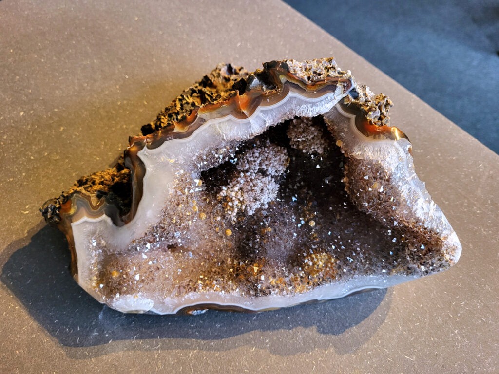 <strong>Agaat, Agaat cluster, 2,8 kg, 142,- euro, nr. 499</strong>

<strong>Beschrijving Agaat.</strong>

Agaat is een veelzijdige edelsteen die bekend staat om zijn prachtige kleurbanden en patronen. Het is een variëteit van het mineraal kwarts, meer specifiek chalcedoon, en wordt vaak gebruikt in sieraden en als decoratieve steen. 
<strong>Algemene kenmerken:</strong>
Agaat is een microkristallijne vorm van kwarts, bestaande uit microscopisch kleine kristallen. 
<strong>Kleuren en patronen:</strong>
Agaat komt voor in vele kleuren, vaak met banden of lagen in verschillende tinten. 
Agaat is een populaire keuze voor het maken van kettingen, armbanden, ringen en andere sieraden vanwege de esthetische aantrekkingskracht en duurzaamheid. 
<strong>Spirituele eigenschappen:</strong>
Agaat wordt vaak geassocieerd met aardende, stabiliserende en beschermende eigenschappen. 
<strong>Helende werking:</strong>
Er wordt aangenomen dat agaat kan helpen bij het verminderen van stress, het bevorderen van emotioneel evenwicht en het versterken van het zelfvertrouwen. 
<strong>Verzorging van agaat:</strong>
Agaat is relatief gemakkelijk te onderhouden. Het kan worden gereinigd met lauw water, de rook van witte salie of palo santo, of door het op een hematiet- of bergkristal-cluster te plaatsen.