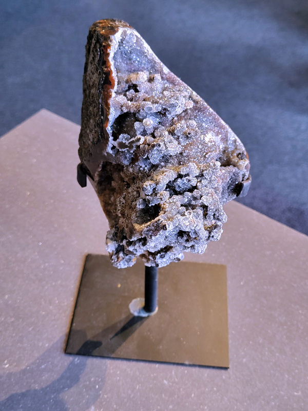 <strong>Agaat op standaard, 2,2 kg, 111,- euro, nr. 54</strong>

<strong>Agaat is een veelzijdige edelsteen die bekend staat om zijn prachtige kleurbanden en patronen.</strong> Het is een variëteit van het mineraal kwarts, meer specifiek chalcedoon, en wordt vaak gebruikt in sieraden en als decoratieve steen. 
<strong>Algemene kenmerken:</strong>
Agaat is een microkristallijne vorm van kwarts, bestaande uit microscopisch kleine kristallen. 
<strong>Kleuren en patronen:</strong>
Agaat komt voor in vele kleuren, vaak met banden of lagen in verschillende tinten. 
Agaat is een populaire keuze voor het maken van kettingen, armbanden, ringen en andere sieraden vanwege de esthetische aantrekkingskracht en duurzaamheid. 
<strong>Spirituele eigenschappen:</strong>
Agaat wordt vaak geassocieerd met aardende, stabiliserende en beschermende eigenschappen. 
<strong>Helende werking:</strong>
Er wordt aangenomen dat agaat kan helpen bij het verminderen van stress, het bevorderen van emotioneel evenwicht en het versterken van het zelfvertrouwen. 
<strong>Verzorging van agaat:</strong>
Agaat is relatief gemakkelijk te onderhouden. Het kan worden gereinigd met lauw water, de rook van witte salie of palo santo, of door het op een hematiet- of bergkristal-cluster te plaatsen.