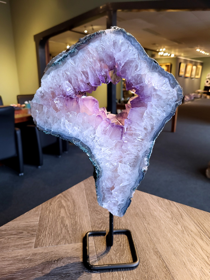 <strong>Amethist, Amethist Portaal, 3,9 kg, 42cm hoog, 174,- euro, nr. 5</strong>

<strong>Amethist is een paarse variëteit van kwarts, bekend om zijn kalmerende en spirituele eigenschappen.</strong> De kleur varieert van licht lila tot diep violet en wordt veroorzaakt door sporen van ijzer en andere elementen. Amethist wordt al eeuwenlang gewaardeerd, zowel vanwege zijn esthetische schoonheid als zijn vermeende genezende en beschermende krachten. 
Amethist is een kwartskristal, vaak te vinden in geodes (holtes in gesteente) of als afzonderlijke kristallen. 
<strong>De kleur varieert van lichtpaars tot diep violet, soms met roze of blauwe tinten. </strong>
De kleurintensiteit kan variëren, waarbij donkerdere amethisten vaak als kwalitatief worden beschouwd. 
Soms vertoont amethist dichroïsme, waarbij je verschillende kleuren kunt zien wanneer je de steen in het licht draait. 

<strong>Vindplaatsen:</strong>
Amethist wordt gevonden in verschillende delen van de wereld, waaronder Brazilië, Uruguay, Zambia, Madagaskar, Rusland en Canada.
Het wordt vaak gevonden in bergachtige gebieden. 

<strong>Gebruik:
Amethist wordt gebruikt in sieraden, decoratieve objecten en als helende steen. </strong>
Het wordt vaak gedragen als hanger, ring of armband, of geplaatst in ruimtes om de energie te zuiveren. 
<strong>Amethist wordt ook gebruikt in meditatie en andere spirituele praktijken. </strong>