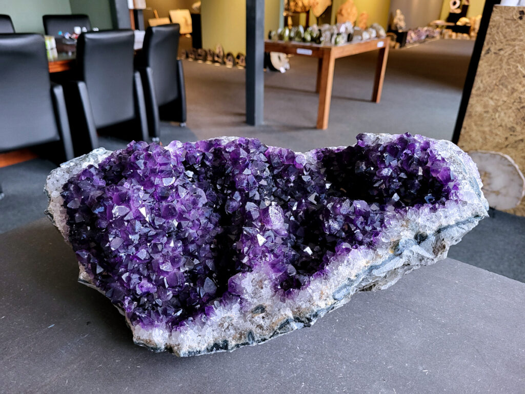 Amethist, Amethist cluster, AAA kwaliteit, 12 kg., 675,- euro, nr. 1

Beschrijving Amethist.
Amethist is een paarse variëteit van kwarts, bekend om zijn kalmerende en spirituele eigenschappen. De kleur varieert van licht lila tot diep violet en wordt veroorzaakt door sporen van ijzer en andere elementen. Amethist wordt al eeuwenlang gewaardeerd, zowel vanwege zijn esthetische schoonheid als zijn vermeende genezende en beschermende krachten. 
Amethist is een kwartskristal, vaak te vinden in geodes (holtes in gesteente) of als afzonderlijke kristallen. 
De kleur varieert van lichtpaars tot diep violet, soms met roze of blauwe tinten. 
De kleurintensiteit kan variëren, waarbij donkerdere amethisten vaak als kwalitatief worden beschouwd. 
Soms vertoont amethist dichroïsme, waarbij je verschillende kleuren kunt zien wanneer je de steen in het licht draait. 

Vindplaatsen:
Amethist wordt gevonden in verschillende delen van de wereld, waaronder Brazilië, Uruguay, Zambia, Madagaskar, Rusland en Canada.
Het wordt vaak gevonden in bergachtige gebieden. 

Gebruik:
Amethist wordt gebruikt in sieraden, decoratieve objecten en als helende steen. 
Het wordt vaak gedragen als hanger, ring of armband, of geplaatst in ruimtes om de energie te zuiveren. 
Amethist wordt ook gebruikt in meditatie en andere spirituele praktijken. 