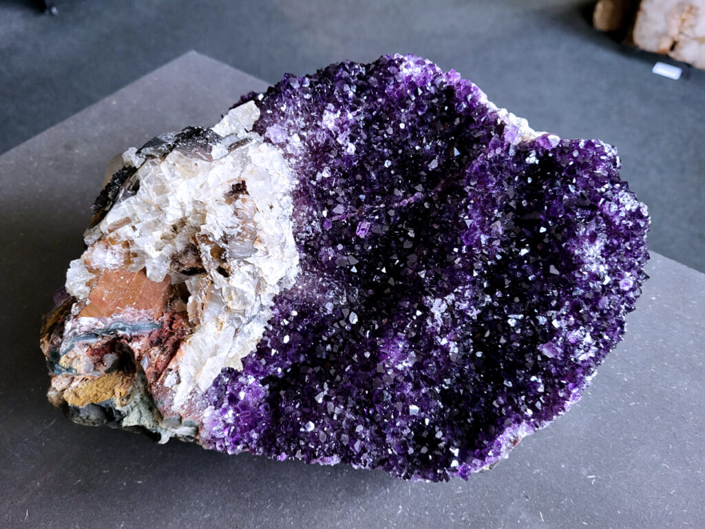 Amethist, Amethist cluster, AAA kwaliteit, 6,6kg, 390,- euro, nr. 513

Beschrijving Amethist.
Amethist is een paarse variëteit van kwarts, bekend om zijn kalmerende en spirituele eigenschappen. De kleur varieert van licht lila tot diep violet en wordt veroorzaakt door sporen van ijzer en andere elementen. Amethist wordt al eeuwenlang gewaardeerd, zowel vanwege zijn esthetische schoonheid als zijn vermeende genezende en beschermende krachten. 
Amethist is een kwartskristal, vaak te vinden in geodes (holtes in gesteente) of als afzonderlijke kristallen. 
De kleur varieert van lichtpaars tot diep violet, soms met roze of blauwe tinten. 
De kleurintensiteit kan variëren, waarbij donkerdere amethisten vaak als kwalitatief worden beschouwd. 
Soms vertoont amethist dichroïsme, waarbij je verschillende kleuren kunt zien wanneer je de steen in het licht draait. 

Vindplaatsen:
Amethist wordt gevonden in verschillende delen van de wereld, waaronder Brazilië, Uruguay, Zambia, Madagaskar, Rusland en Canada.
Het wordt vaak gevonden in bergachtige gebieden. 

Gebruik:
Amethist wordt gebruikt in sieraden, decoratieve objecten en als helende steen. 
Het wordt vaak gedragen als hanger, ring of armband, of geplaatst in ruimtes om de energie te zuiveren. 
Amethist wordt ook gebruikt in meditatie en andere spirituele praktijken. 
