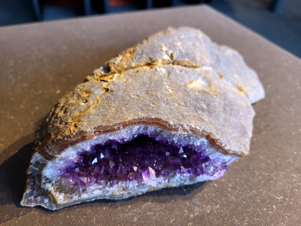 <strong>Amethist Cluster, Amethist, 1,3 kg, 34,- euro, nr. 3</strong>

Beschrijving Amethist.
<strong>Amethist is een paarse variëteit van kwarts, bekend om zijn kalmerende en spirituele eigenschappen.</strong> De kleur varieert van licht lila tot diep violet en wordt veroorzaakt door sporen van ijzer en andere elementen. Amethist wordt al eeuwenlang gewaardeerd, zowel vanwege zijn esthetische schoonheid als zijn vermeende genezende en beschermende krachten. 
Amethist is een kwartskristal, vaak te vinden in geodes (holtes in gesteente) of als afzonderlijke kristallen. 
<strong>De kleur varieert van lichtpaars tot diep violet, soms met roze of blauwe tinten. </strong>
De kleurintensiteit kan variëren, waarbij donkerdere amethisten vaak als kwalitatief worden beschouwd. 
Soms vertoont amethist dichroïsme, waarbij je verschillende kleuren kunt zien wanneer je de steen in het licht draait. 

<strong>Vindplaatsen:</strong>
Amethist wordt gevonden in verschillende delen van de wereld, waaronder Brazilië, Uruguay, Zambia, Madagaskar, Rusland en Canada.
Het wordt vaak gevonden in bergachtige gebieden. 

<strong>Gebruik:</strong>
Amethist wordt gebruikt in sieraden, decoratieve objecten en als helende steen. 
Het wordt vaak gedragen als hanger, ring of armband, of geplaatst in ruimtes om de energie te zuiveren. 
<strong>Amethist wordt ook gebruikt in meditatie en andere spirituele praktijken. 
</strong>