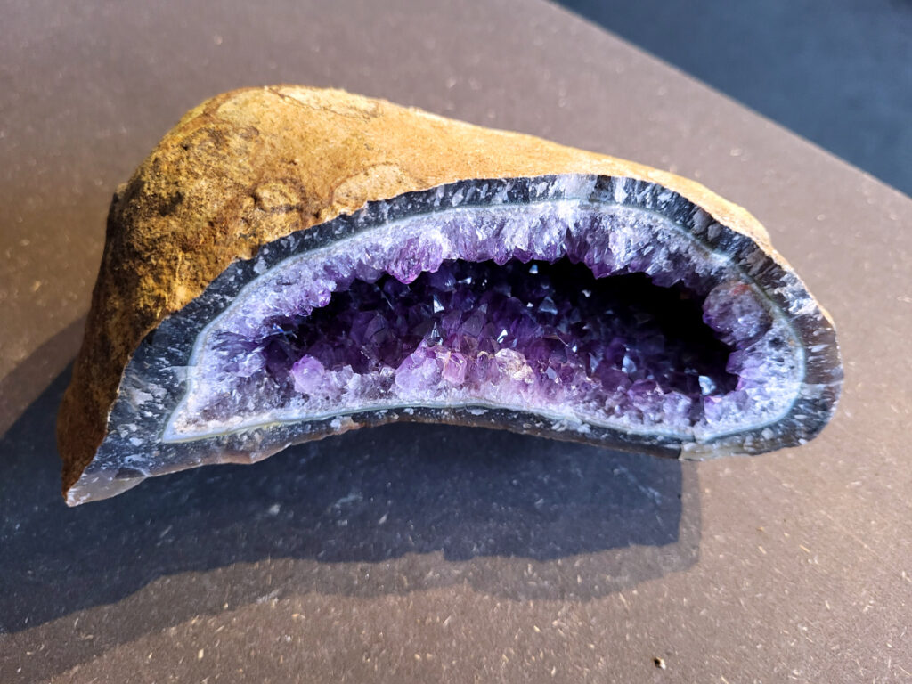 <strong>Amethist Cluster, Amethist, 2,1 kg, 52,- euro, nr. 13</strong>

Beschrijving Amethist.
<strong>Amethist is een paarse variëteit van kwarts, bekend om zijn kalmerende en spirituele eigenschappen. </strong>De kleur varieert van licht lila tot diep violet en wordt veroorzaakt door sporen van ijzer en andere elementen. Amethist wordt al eeuwenlang gewaardeerd, zowel vanwege zijn esthetische schoonheid als zijn vermeende genezende en beschermende krachten. 
<strong>Amethist is een kwartskristal, vaak te vinden in geodes (holtes in gesteente) of als afzonderlijke kristallen. 
De kleur varieert van lichtpaars tot diep violet, soms met roze of blauwe tinten. </strong>
De kleurintensiteit kan variëren, waarbij donkerdere amethisten vaak als kwalitatief worden beschouwd. 
Soms vertoont amethist dichroïsme, waarbij je verschillende kleuren kunt zien wanneer je de steen in het licht draait. 

<strong>Vindplaatsen:</strong>
Amethist wordt gevonden in verschillende delen van de wereld, waaronder Brazilië, Uruguay, Zambia, Madagaskar, Rusland en Canada.
Het wordt vaak gevonden in bergachtige gebieden. 

<strong>Gebruik:</strong>
Amethist wordt gebruikt in sieraden, decoratieve objecten en als helende steen. 
Het wordt vaak gedragen als hanger, ring of armband, of geplaatst in ruimtes om de energie te zuiveren. 
<strong>Amethist wordt ook gebruikt in meditatie en andere spirituele praktijken. 
</strong>