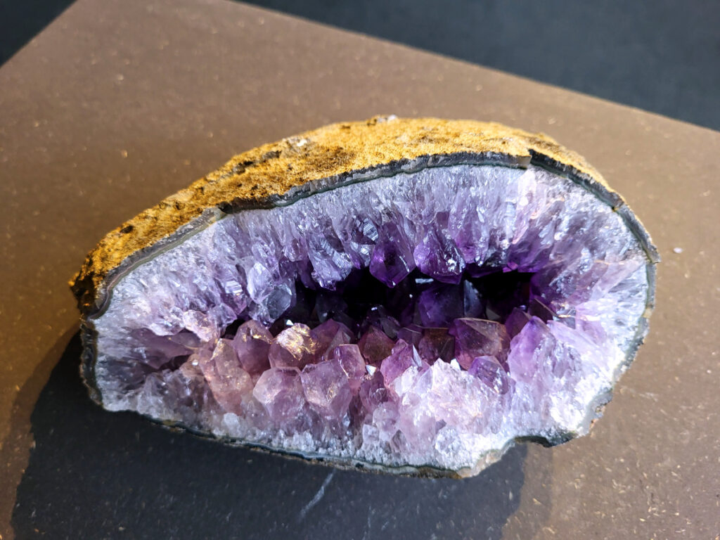 <strong>Amethist Cluster, Amethist, 3 kg, 75,- euro, nr. 10</strong>

Beschrijving Amethist.
<strong>Amethist is een paarse variëteit van kwarts, bekend om zijn kalmerende en spirituele eigenschappen.</strong> De kleur varieert van licht lila tot diep violet en wordt veroorzaakt door sporen van ijzer en andere elementen. Amethist wordt al eeuwenlang gewaardeerd, zowel vanwege zijn esthetische schoonheid als zijn vermeende genezende en beschermende krachten. 
<strong>Amethist is een kwartskristal, vaak te vinden in geodes (holtes in gesteente) of als afzonderlijke kristallen. 
De kleur varieert van lichtpaars tot diep violet, soms met roze of blauwe tinten. </strong>
De kleurintensiteit kan variëren, waarbij donkerdere amethisten vaak als kwalitatief worden beschouwd. 
Soms vertoont amethist dichroïsme, waarbij je verschillende kleuren kunt zien wanneer je de steen in het licht draait. 

<strong>Vindplaatsen:</strong>
Amethist wordt gevonden in verschillende delen van de wereld, waaronder Brazilië, Uruguay, Zambia, Madagaskar, Rusland en Canada.
Het wordt vaak gevonden in bergachtige gebieden. 

<strong>Gebruik:</strong>
Amethist wordt gebruikt in sieraden, decoratieve objecten en als helende steen. 
Het wordt vaak gedragen als hanger, ring of armband, of geplaatst in ruimtes om de energie te zuiveren. 
<strong>Amethist wordt ook gebruikt in meditatie en andere spirituele praktijken. </strong>