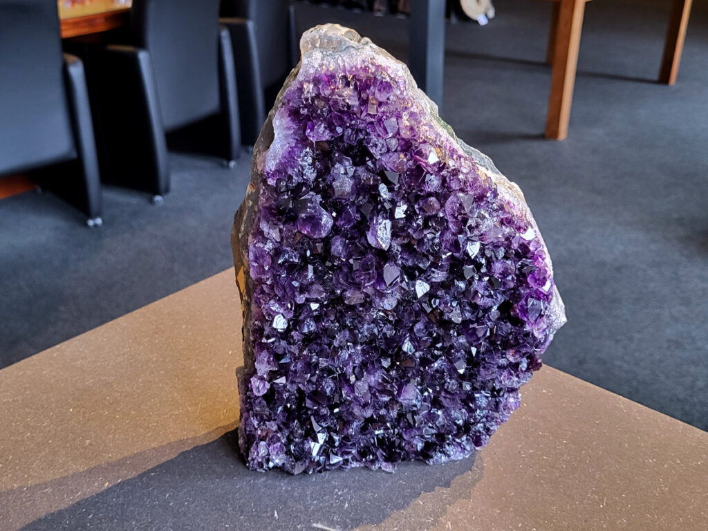 <strong>Amethist Cluster, Amethist, 4,7 kg, 280,- euro, nr. 5</strong>

Beschrijving Amethist.
<strong>Amethist is een paarse variëteit van kwarts, bekend om zijn kalmerende en spirituele eigenschappen.</strong> De kleur varieert van licht lila tot diep violet en wordt veroorzaakt door sporen van ijzer en andere elementen. Amethist wordt al eeuwenlang gewaardeerd, zowel vanwege zijn esthetische schoonheid als zijn vermeende genezende en beschermende krachten. 
<strong>Amethist is een kwartskristal, vaak te vinden in geodes (holtes in gesteente) of als afzonderlijke kristallen. 
De kleur varieert van lichtpaars tot diep violet, soms met roze of blauwe tinten. </strong>
De kleurintensiteit kan variëren, waarbij donkerdere amethisten vaak als kwalitatief worden beschouwd. 
Soms vertoont amethist dichroïsme, waarbij je verschillende kleuren kunt zien wanneer je de steen in het licht draait. 

<strong>Vindplaatsen:</strong>
Amethist wordt gevonden in verschillende delen van de wereld, waaronder Brazilië, Uruguay, Zambia, Madagaskar, Rusland en Canada.
Het wordt vaak gevonden in bergachtige gebieden. 

<strong>Gebruik:</strong>
Amethist wordt gebruikt in sieraden, decoratieve objecten en als helende steen. 
Het wordt vaak gedragen als hanger, ring of armband, of geplaatst in ruimtes om de energie te zuiveren. 
<strong>Amethist wordt ook gebruikt in meditatie en andere spirituele praktijken. </strong>