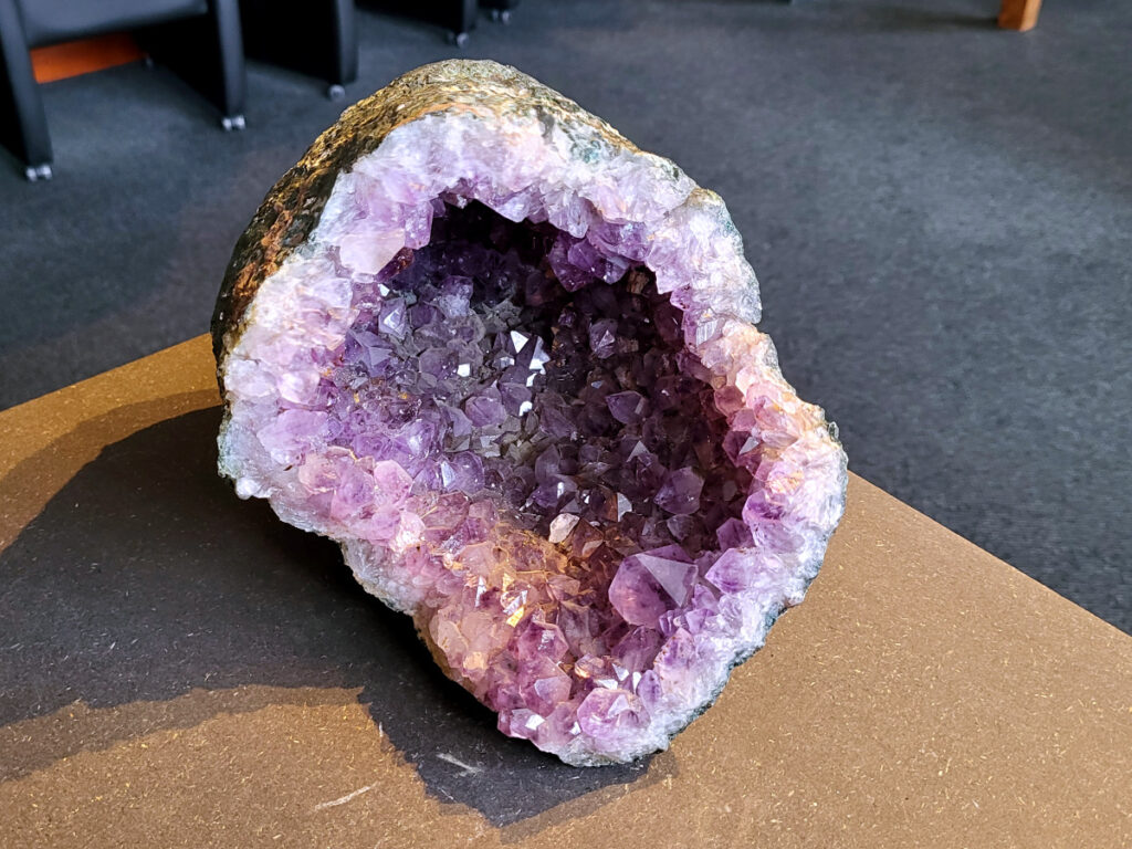 <strong>Amethist Cluster, Amethist, 5,5 kg, 145,- euro, nr. 6</strong>

Beschrijving Amethist.
<strong>Amethist is een paarse variëteit van kwarts, bekend om zijn kalmerende en spirituele eigenschappen.</strong> De kleur varieert van licht lila tot diep violet en wordt veroorzaakt door sporen van ijzer en andere elementen. Amethist wordt al eeuwenlang gewaardeerd, zowel vanwege zijn esthetische schoonheid als zijn vermeende genezende en beschermende krachten. 
<strong>Amethist is een kwartskristal, vaak te vinden in geodes (holtes in gesteente) of als afzonderlijke kristallen. 
De kleur varieert van lichtpaars tot diep violet, soms met roze of blauwe tinten. </strong>
De kleurintensiteit kan variëren, waarbij donkerdere amethisten vaak als kwalitatief worden beschouwd. 
Soms vertoont amethist dichroïsme, waarbij je verschillende kleuren kunt zien wanneer je de steen in het licht draait. 

<strong>Vindplaatsen:</strong>
Amethist wordt gevonden in verschillende delen van de wereld, waaronder Brazilië, Uruguay, Zambia, Madagaskar, Rusland en Canada.
Het wordt vaak gevonden in bergachtige gebieden. 

<strong>Gebruik:</strong>
Amethist wordt gebruikt in sieraden, decoratieve objecten en als helende steen. 
Het wordt vaak gedragen als hanger, ring of armband, of geplaatst in ruimtes om de energie te zuiveren. 
<strong>Amethist wordt ook gebruikt in meditatie en andere spirituele praktijken. 

</strong>