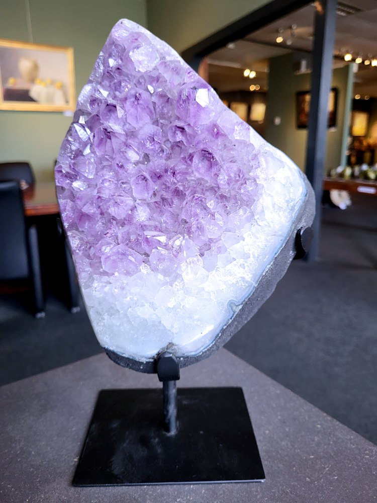 Amethist-op-standaard-amethist-8,1kg-245-euro, nr. 3

Beschrijving Amethist.
Amethist is een paarse variëteit van kwarts, bekend om zijn kalmerende en spirituele eigenschappen. De kleur varieert van licht lila tot diep violet en wordt veroorzaakt door sporen van ijzer en andere elementen. Amethist wordt al eeuwenlang gewaardeerd, zowel vanwege zijn esthetische schoonheid als zijn vermeende genezende en beschermende krachten. 
Amethist is een kwartskristal, vaak te vinden in geodes (holtes in gesteente) of als afzonderlijke kristallen. 
De kleur varieert van lichtpaars tot diep violet, soms met roze of blauwe tinten. 
De kleurintensiteit kan variëren, waarbij donkerdere amethisten vaak als kwalitatief worden beschouwd. 
Soms vertoont amethist dichroïsme, waarbij je verschillende kleuren kunt zien wanneer je de steen in het licht draait. 

Vindplaatsen:
Amethist wordt gevonden in verschillende delen van de wereld, waaronder Brazilië, Uruguay, Zambia, Madagaskar, Rusland en Canada.
Het wordt vaak gevonden in bergachtige gebieden. 

Gebruik:
Amethist wordt gebruikt in sieraden, decoratieve objecten en als helende steen. 
Het wordt vaak gedragen als hanger, ring of armband, of geplaatst in ruimtes om de energie te zuiveren. 
Amethist wordt ook gebruikt in meditatie en andere spirituele praktijken. 


