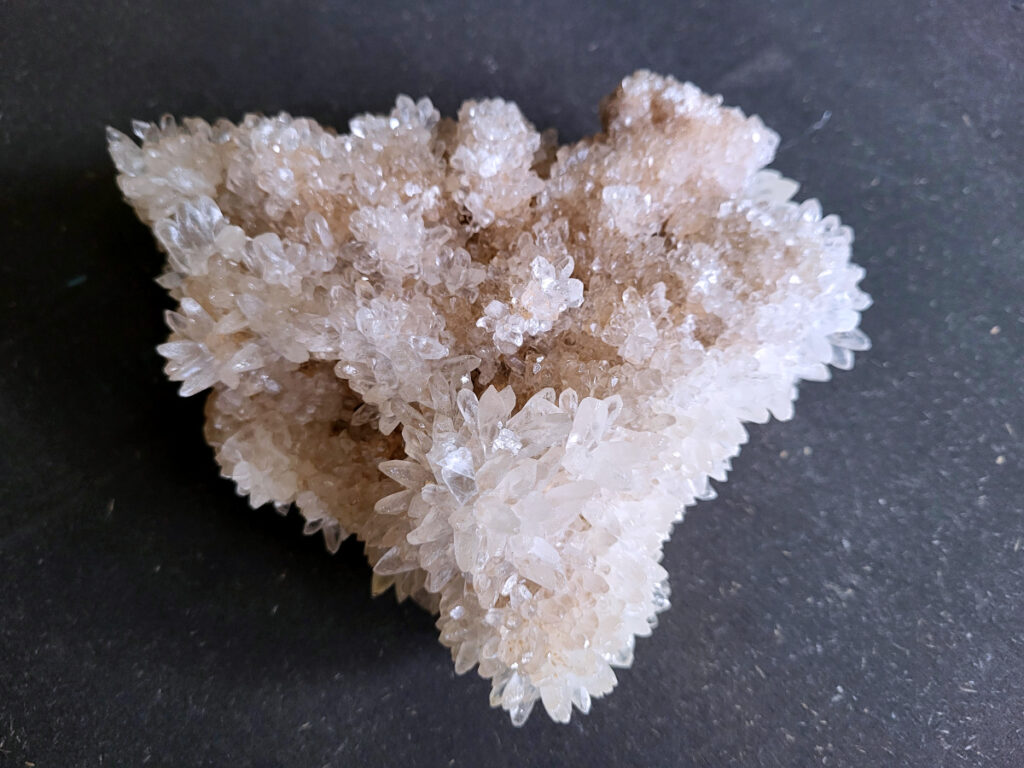 Calciet, Hondentandencalciet, cluster, geode, 1,1kg, 25,- euro, nr. 41

Beschrijving Hondentandcalciet.

Hondentandcalciet, ook wel Starburst calciet genoemd, is een vorm van calciet die bekend staat om zijn unieke, ruwe kristalstructuur die lijkt op hondentanden of varkensstanden. Het wordt gewaardeerd om zijn zachte, heldere uitstraling en wordt vaak gevonden in combinatie met andere mineralen zoals fluoriet. 
Kenmerken van Hondentandcalciet:
Kristalstructuur:
De kristallen zijn grillig, puntig en helder gevormd, wat een ruwe, natuurlijke uitstraling geeft. 
Kleur:
Meestal wit of licht van kleur, soms met bruine tinten of bedekt met andere mineralen zoals fluoriet. 
Energie:
Bekend om zijn zachte, lichtkracht en wordt geassocieerd met diepe transformaties en het openen van het bewustzijn. 
Vormen:
Te vinden in ruwe, onbewerkte vormen, maar ook op standaard of in combinatie met andere mineralen. 
Spiritueel:
Wordt gebruikt voor spirituele doeleinden, zoals meditatie en het openen van het bewustzijn. 