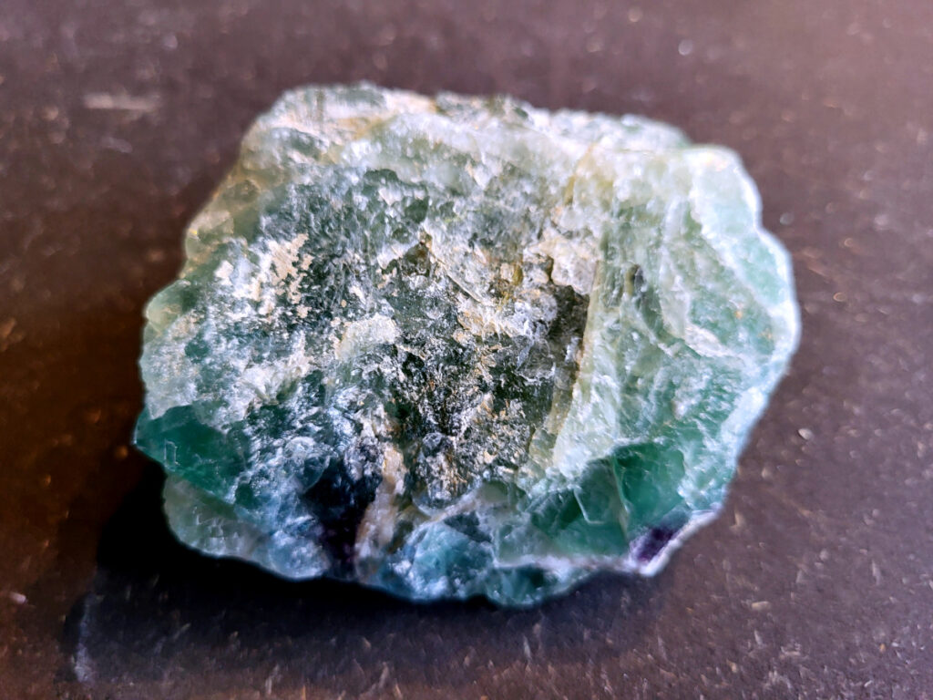 <strong>Fluoriet, brok groene fluoriet, 0,4 kg, 12,- euro, nr. 3</strong>

Fluoriet,
<strong>Fluoriet is een veelzijdig, kleurrijk mineraal (calciumfluoride) dat bekend staat om zijn sterke concentratie bevorderende, beschermende en reinigende werking op de geest.</strong> Het ordent chaos, helpt bij studie en emotionele stabiliteit, en wordt vaak gebruikt om elektromagnetische straling te verminderen. Het mineraal fluoresceert vaak onder UV-licht.
<strong>Kernmerken van Fluoriet:</strong>
Kleur: Zeer variabel, inclusief paars, groen, blauw, geel en kleurloos.
Hardheid: 4 op de schaal van Mohs (tamelijk zacht).
Kristalstelsel: Kubisch, vaak als octaëder.
Toepassing: Geliefd bij verzamelaars, spirituele beoefenaars (meditatie) en industrieel gebruikt als vloeispaat (vloeimiddel bij metaalsmelting).
<strong>Spirituele en Emotionele Werking:</strong>
Focus & Studie: Helpt bij het ordenen van gedachten, concentratie en snelle informatieverwerking.
Bescherming: Werkt stabiliserend, vergroot het zelfvertrouwen en helpt tegen negatieve invloeden of overprikkeling.
Emotionele balans: Brengt emoties in evenwicht en helpt bij het loslaten van oude patronen. 
<strong>Fysieke Werking (Edelsteentherapie):</strong>
Botten en Gebit: Ondersteunt de gezondheid van tanden, botten en gewrichten.
Pijnbestrijding: Wordt ingezet bij zenuwpijn, gordelroos en artritis.
Reiniging: Zou helpen bij ontgifting en het immuunsysteem versterken. 

<strong>Kleurvariaties en Specifieke Werking:
Groene Fluoriet: Reinigt de aura, bevordert emotionele healing en nuchterheid.
Paarse Fluoriet: Stimuleert de intuïtie en spirituele wijsheid.
Blauwe Fluoriet: Ondersteunt communicatie en creativiteit.
Regenboogfluoriet: Combineert de eigenschappen van de verschillende kleuren. 

</strong>