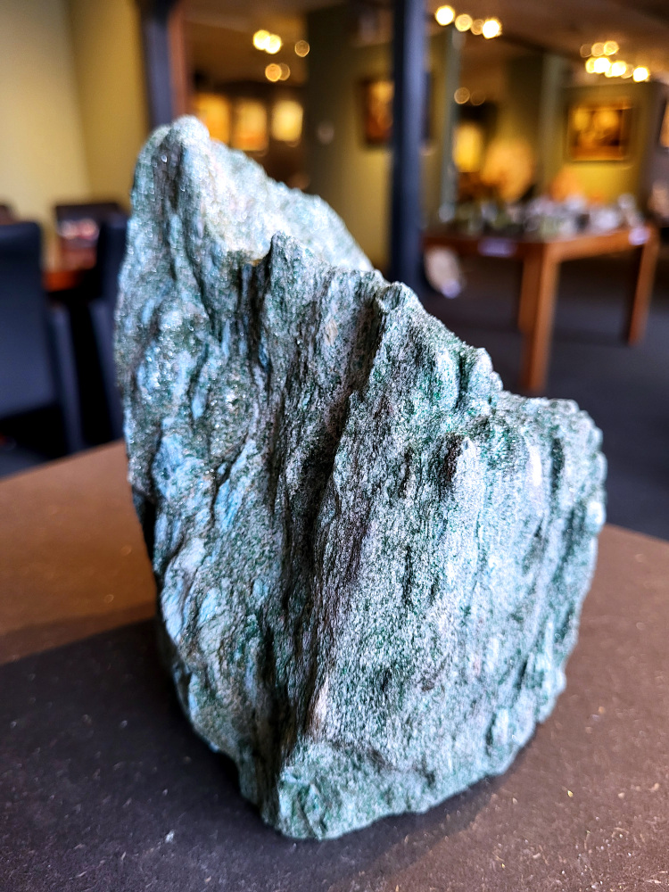 <strong>Fuchsiet, 2,9 kg, 16cm hoog, 44,- euro, nr. 4</strong>

Beschrijving, Fuchsiet.

<strong>Fuchsiet is een groene, chroomhoudende variant van muscoviet, een soort mica. Het dankt zijn kleur aan de aanwezigheid van chroom en wordt vaak gevonden in metamorf gesteente zoals gneis en schist, maar ook in stollingsgesteente zoals graniet.</strong> Fuchsiet wordt beschouwd als een steen die inzicht, zelfbeschikking en bescherming bevordert. 
<strong>Eigenschappen en werking:</strong>
<strong>Inzicht en zelfbeschikking:</strong>
Fuchsiet helpt bij het verkrijgen van inzicht in relaties en bevordert een gezonde interactie met anderen, zonder wederzijdse afhankelijkheid. 
<strong>Bescherming:</strong>
De steen beschermt tegen negatieve energieën en emoties van anderen en helpt je om je grenzen duidelijker te stellen. 
<strong>Emotionele balans:</strong>
Fuchsiet kan helpen bij het loslaten van negatieve emoties en het overwinnen van een slachtofferrol. 
<strong>Fysieke ondersteuning:</strong>
Sommige bronnen beweren dat fuchsiet ondersteunend kan werken bij allergieën, jeuk, ontstekingen, bloed- en zenuwklachten. 
<strong>Combinaties:</strong>
Fuchsiet wordt vaak gevonden met robijn, waarbij de combinatie krachtige energie, moed en doorzettingsvermogen kan versterken. 
<strong>Chakra:</strong>
Fuchsiet wordt geassocieerd met het hartchakra (4e chakra). 
<strong>Verzorging:</strong>
Fuchsiet kan beter niet met water gereinigd worden, aldus Edelstenen en Mineralen. 
Andere bronnen suggereren dat het reinigen onder stromend water of een nacht in zout water een optie is. 
<strong>Vindplaatsen:
Brazilië is een bekende vindplaats van fuchsiet. </strong>