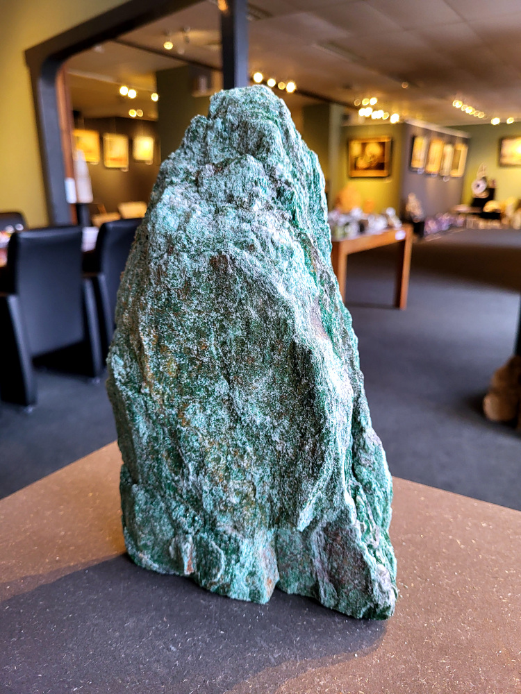 <strong>Fuchsiet, 4,3 kg, 27cm hoog, 69,- euro, nr. 5</strong>

Beschrijving, Fuchsiet.

<strong>Fuchsiet is een groene, chroomhoudende variant van muscoviet, een soort mica. Het dankt zijn kleur aan de aanwezigheid van chroom en wordt vaak gevonden in metamorf gesteente zoals gneis en schist, maar ook in stollingsgesteente zoals graniet.</strong> Fuchsiet wordt beschouwd als een steen die inzicht, zelfbeschikking en bescherming bevordert. 
<strong>Eigenschappen en werking:</strong>
<strong>Inzicht en zelfbeschikking:</strong>
Fuchsiet helpt bij het verkrijgen van inzicht in relaties en bevordert een gezonde interactie met anderen, zonder wederzijdse afhankelijkheid. 
Bescherming:
De steen beschermt tegen negatieve energieën en emoties van anderen en helpt je om je grenzen duidelijker te stellen. 
<strong>Emotionele balans:</strong>
Fuchsiet kan helpen bij het loslaten van negatieve emoties en het overwinnen van een slachtofferrol. 
<strong>Fysieke ondersteuning:</strong>
Sommige bronnen beweren dat fuchsiet ondersteunend kan werken bij allergieën, jeuk, ontstekingen, bloed- en zenuwklachten. 
<strong>Combinaties:</strong>
Fuchsiet wordt vaak gevonden met robijn, waarbij de combinatie krachtige energie, moed en doorzettingsvermogen kan versterken. 
<strong>Chakra:</strong>
Fuchsiet wordt geassocieerd met het hartchakra (4e chakra). 
<strong>Verzorging:</strong>
Fuchsiet kan beter niet met water gereinigd worden, aldus Edelstenen en Mineralen. 
Andere bronnen suggereren dat het reinigen onder stromend water of een nacht in zout water een optie is. 
<strong>Vindplaatsen:
Brazilië is een bekende vindplaats van fuchsiet. </strong>