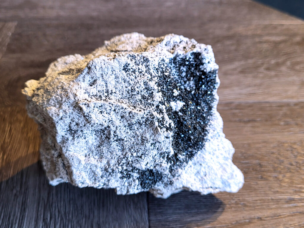 <strong>Kwarts, Druzy Kwarts, 0,7 kg, 7,- euro, nr. 3</strong>

Kwarts, Druzy Kwarts op een matrix van Calciet

<strong>Druzy kwarts op een matrix van calciet (waarschijnlijk ijzer/mangaan-oxiden).</strong>
De donkere kleine kwartskristalletjes (druzy) glinsteren je tegemoet.
De ondergrond is wit/grijs en dat is typisch voor calciet 
<strong>De donkere kleur komt vaak door mineralen zoals hematiet of mangaan die tijdens de vorming in de kwarts zijn gekomen.</strong>
Druzy kwarts op calciet met donkere mineralisatie.
Met een sterke glitter. Dat is typisch druzy.
<strong>Spiritueel :
Druzy kwarts wordt vaak gezien als versterker van energie en helderheid.
Door de donkere mineralen wordt hij soms gezien als beschermend / aardend.
Zulke natuurlijke stukken komen vaak uit Marokko of China.
</strong>