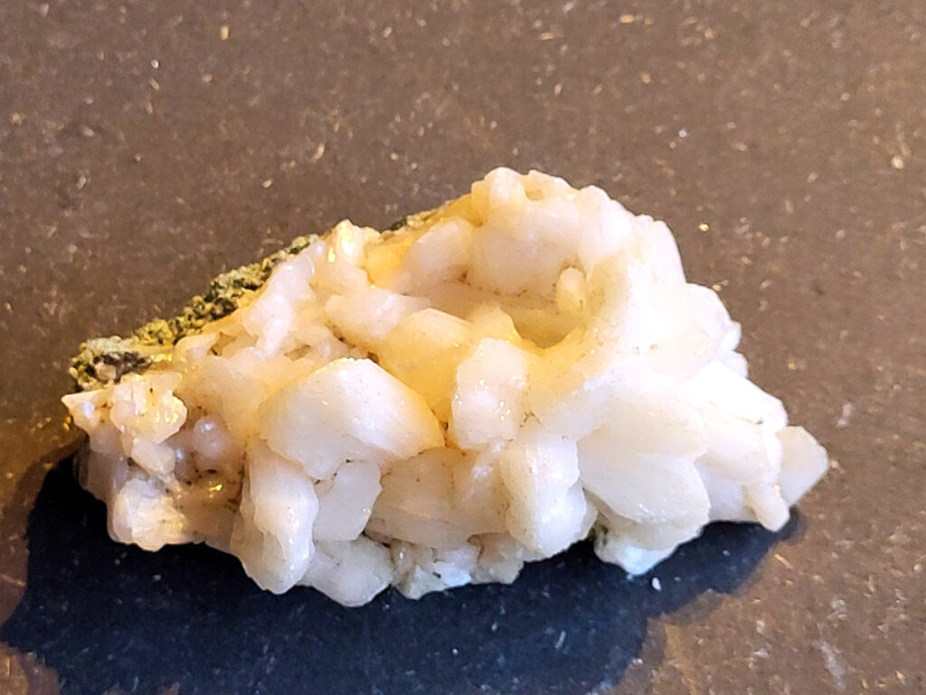 <strong>Stilbiet Cluster, 0,3 kg, 7,- euro, nr. 1</strong>

Stilbiet,
<strong>De waaier- of bundelvormige kristallen met een zijdeachtige glans en soms lichtgroen-geelatige gloed zijn typisch voor stilbiet.</strong>
De helder witte tot doorschijnende kubusvormige kristallen aan de basis zijn apofyliet.
De gele of groenige zweem kan komen van een lichte epidoot- of prehniet-insluiting, of een natuurlijke oxidatie aan het oppervlak.
Energetische werking:
<strong>Stilbiet opent het hart en helpt loslaten van zorgen; het is zacht, troostend en bevordert vertrouwen in de loop van het leven.</strong>
Apofyliet versterkt intuïtie, helderheid en spirituele verbinding — een “lichtbrenger” die energie zuivert in een ruimte.
Samen vormen ze een kalmerende, hoogtrillende combinatie die ideaal is voor meditatie, healingruimtes of slaapkamers (voor rust en inzicht).
<strong>Zorgtip:</strong>
Houd ze uit direct zonlicht (kan verkleuren) en reinig liever met klank, maanlicht of wierook in plaats van water — apofyliet lost iets op bij langdurig vocht.
 <strong>Uiterlijk:</strong>
De perzik- tot crème-witte kleur,
De glanzende, waaier- of bloemvormige kristalstructuur,
De zachte, zijdeachtige glans (bijna parelmoerachtig),
al die kenmerken passen heel goed bij stilbiet.
De ronde, lichtgrijze korrelige bol bovenop kan een heulandiet- of chalcedoon-vorming zijn die samen met de stilbiet is gegroeid.
<strong>Energetische betekenis:</strong>
Stilbiet hoort bij het hart en het kruinchakra — een zachte, troostende energie die helpt bij het loslaten van oude patronen en het verbinden met hogere leiding.
Ze ondersteunt intuïtie, dromen en zachtheid in relaties — een heel liefdevolle steen om in huis te hebben, vooral bij healing- of slaapruimtes.