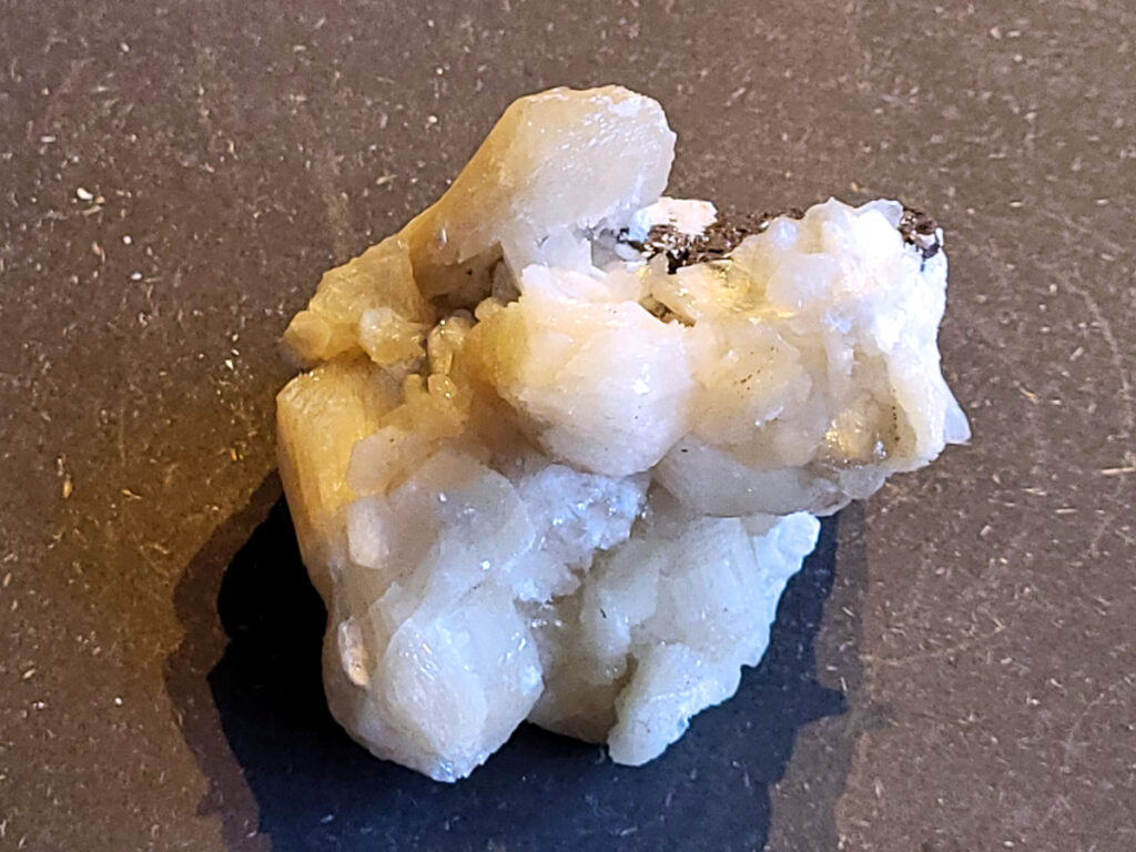 <strong>Stilbiet Cluster, 0,4 kg, 8,- euro, nr. 2</strong>

Stilbiet,
<strong>De waaier- of bundelvormige kristallen met een zijdeachtige glans en soms lichtgroen-geelatige gloed zijn typisch voor stilbiet.</strong>
De helder witte tot doorschijnende kubusvormige kristallen aan de basis zijn apofyliet.
De gele of groenige zweem kan komen van een lichte epidoot- of prehniet-insluiting, of een natuurlijke oxidatie aan het oppervlak.
Energetische werking:
<strong>Stilbiet opent het hart en helpt loslaten van zorgen; het is zacht, troostend en bevordert vertrouwen in de loop van het leven.</strong>
Apofyliet versterkt intuïtie, helderheid en spirituele verbinding — een “lichtbrenger” die energie zuivert in een ruimte.
Samen vormen ze een kalmerende, hoogtrillende combinatie die ideaal is voor meditatie, healingruimtes of slaapkamers (voor rust en inzicht).
Zorgtip:
Houd ze uit direct zonlicht (kan verkleuren) en reinig liever met klank, maanlicht of wierook in plaats van water — apofyliet lost iets op bij langdurig vocht.
 <strong>Uiterlijk:</strong>
De perzik- tot crème-witte kleur,
De glanzende, waaier- of bloemvormige kristalstructuur,
De zachte, zijdeachtige glans (bijna parelmoerachtig),
al die kenmerken passen heel goed bij stilbiet.
De ronde, lichtgrijze korrelige bol bovenop kan een heulandiet- of chalcedoon-vorming zijn die samen met de stilbiet is gegroeid.
Energetische betekenis:
Stilbiet hoort bij het hart en het kruinchakra — een zachte, troostende energie die helpt bij het loslaten van oude patronen en het verbinden met hogere leiding.
Ze ondersteunt intuïtie, dromen en zachtheid in relaties — een heel liefdevolle steen om in huis te hebben, vooral bij healing- of slaapruimtes.