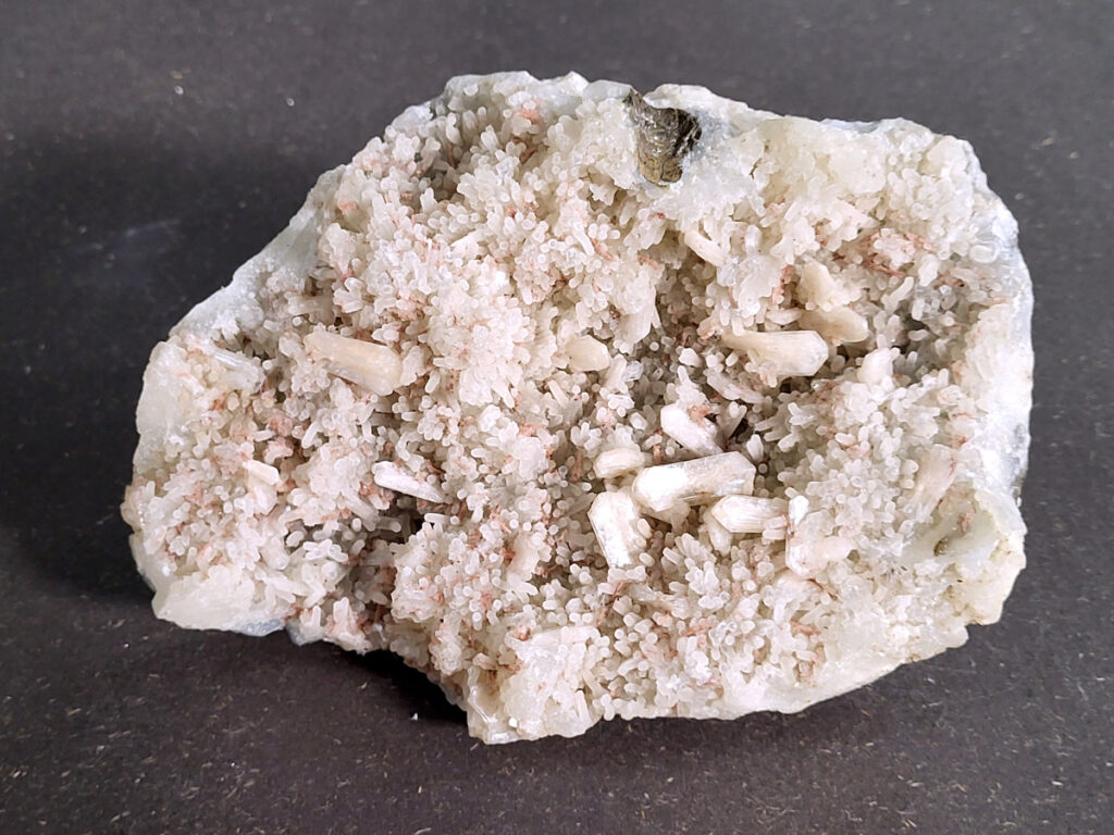 <strong>Zeoliet met Stilbiet, 1,4 kg, 26,- euro, nr. 14</strong>

<strong>Zeoliet met Stilbiet,</strong>

Mineralencluster, waarschijnlijk Zeoliet met Stilbiet,
of Heulandiet op Chalcedoon/kwarts. 

<strong>Heel veel kleine bolvormige kristalletjes (dat heet een botryoïdale structuur).
Daartussen zitten langwerpige, witte “staafjes” of bladvormige kristallen.</strong>
De kleur is wit tot licht crème.
Het geheel zit op een lichtgrijze tot witte matrix.
Dat patroon komt heel vaak voor bij zeolieten uit basaltgesteente (bijvoorbeeld uit India of IJsland).
De onderdelen zijn kleine bolletjes: chalcedoon of druzy kwarts.

<strong>De langwerpige kristallen: stilbiet of heulandiet (zeolieten)
Zulke stukken worden vaak verkocht als Stilbite on chalcedony of Heulandite zeolite cluster.</strong>