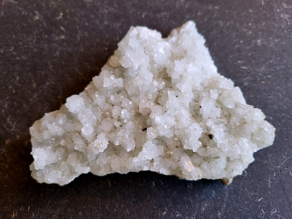 Apofyliet op matrix, 110 gram, 10cm doorsnee, 6,- euro

Apofyliet op matrix, beschrijving

apofyliet op matrix
De doorzichtige tot melkachtige blokvormige kristallen zijn typisch voor apofyliet.
Apofyliet vormt vaak vierkante of rechthoekige kristallen met vlakke toppen.
De groenige korrelige ondergrond is een zeolietmatrix (bijvoorbeeld stilbiet of heulandiet).
Dit soort combinaties komt vaak uit India (Maharashtra regio).
Kenmerken van apofyliet
Kleur: transparant, wit, soms lichtgroen
Kristalvorm: kubusachtig / blokvormig met glanzende vlakken
Glans: glasachtig
Vaak gevonden samen met: stilbiet, heulandiet, calciet
Apofyliet is een helder of wit mineraal dat behoort tot de groep van de calciumsilicaten. Het wordt voornamelijk gevonden in vulkanische gesteenten, vooral in de buurt van breuken en scheuren. In de spirituele wereld wordt Apofyliet beschouwd als een krachtige steen met een hoge vibratie die helpt bij het openen en activeren van de hogere chakra's, met name het derde oog en de kruinchakra.
Apofyliet werkt ondersteunend bij innerlijke druk en angsten, tevens goede steen om fixaties en rigiditeit los te laten. De steen spoort je aan om je thuis te voelen in je eigen lichaam. Dit maakt het een zeer goede steen voor meditatieve doeleinden. De energie van Apofyliet wordt ook geassocieerd met helderheid, zuiverheid en zuivering. Het kan worden gebruikt om negatieve energieën en emoties te verwijderen en om een gevoel van kalmte en vrede te bevorderen. Het kan ook helpen bij het verminderen van stress en angst en het bevorderen van innerlijke rust en harmonie.
Fysiek wordt Apofyliet geassocieerd met het versterken van het immuunsysteem en het bevorderen van een gezonde spijsvertering. Het kan ook worden gebruikt om hoofdpijn, migraine en andere pijnlijke aandoeningen te verlichten. Het loslaten van fixaties en rigiditeit kan ook verlichting bieden voor fysieke spanning in het lichaam.
Over het algemeen wordt Apofyliet beschouwd als een krachtige steen voor spirituele groei en genezing, en het kan een waardevolle aanvulling zijn op meditatie- en genezingspraktijken. Het biedt emotionele en mentale ondersteuning door het helpen loslaten van fixaties en rigiditeit, en het bevorderen van innerlijke rust en harmonie. Het biedt ook fysieke voordelen, zoals het versterken van het immuunsysteem en het verlichten van hoofdpijn en andere pijnlijke aandoeningen.