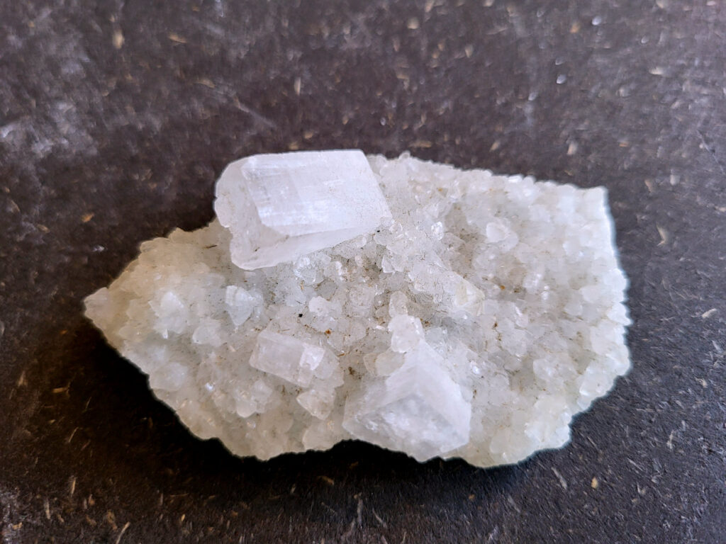 Apofyliet op matrix, 34 gram, 7cm doorsnee, 4,- euro, nr. 9

Apofyliet op matrix, beschrijving

apofyliet op matrix
De doorzichtige tot melkachtige blokvormige kristallen zijn typisch voor apofyliet.
Apofyliet vormt vaak vierkante of rechthoekige kristallen met vlakke toppen.
De groenige korrelige ondergrond is een zeolietmatrix (bijvoorbeeld stilbiet of heulandiet).
Dit soort combinaties komt vaak uit India (Maharashtra regio).
Kenmerken van apofyliet
Kleur: transparant, wit, soms lichtgroen
Kristalvorm: kubusachtig / blokvormig met glanzende vlakken
Glans: glasachtig
Vaak gevonden samen met: stilbiet, heulandiet, calciet
Apofyliet is een helder of wit mineraal dat behoort tot de groep van de calciumsilicaten. Het wordt voornamelijk gevonden in vulkanische gesteenten, vooral in de buurt van breuken en scheuren. In de spirituele wereld wordt Apofyliet beschouwd als een krachtige steen met een hoge vibratie die helpt bij het openen en activeren van de hogere chakra's, met name het derde oog en de kruinchakra.
Apofyliet werkt ondersteunend bij innerlijke druk en angsten, tevens goede steen om fixaties en rigiditeit los te laten. De steen spoort je aan om je thuis te voelen in je eigen lichaam. Dit maakt het een zeer goede steen voor meditatieve doeleinden. De energie van Apofyliet wordt ook geassocieerd met helderheid, zuiverheid en zuivering. Het kan worden gebruikt om negatieve energieën en emoties te verwijderen en om een gevoel van kalmte en vrede te bevorderen. Het kan ook helpen bij het verminderen van stress en angst en het bevorderen van innerlijke rust en harmonie.
Fysiek wordt Apofyliet geassocieerd met het versterken van het immuunsysteem en het bevorderen van een gezonde spijsvertering. Het kan ook worden gebruikt om hoofdpijn, migraine en andere pijnlijke aandoeningen te verlichten. Het loslaten van fixaties en rigiditeit kan ook verlichting bieden voor fysieke spanning in het lichaam.
Over het algemeen wordt Apofyliet beschouwd als een krachtige steen voor spirituele groei en genezing, en het kan een waardevolle aanvulling zijn op meditatie- en genezingspraktijken. Het biedt emotionele en mentale ondersteuning door het helpen loslaten van fixaties en rigiditeit, en het bevorderen van innerlijke rust en harmonie. Het biedt ook fysieke voordelen, zoals het versterken van het immuunsysteem en het verlichten van hoofdpijn en andere pijnlijke aandoeningen.


