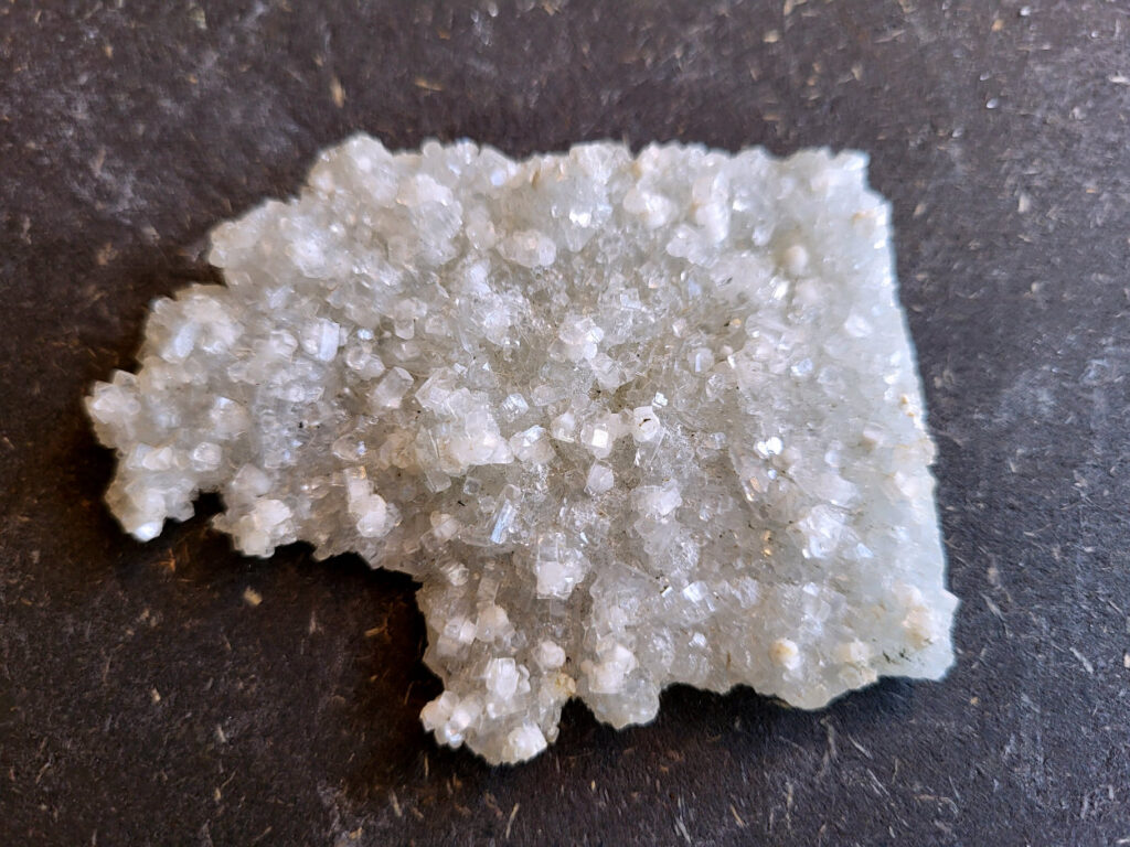 Apofyliet op matrix, 36 gram, 7cm doorsnee, 4,- euro, nr. 10

Apofyliet op matrix, beschrijving

apofyliet op matrix
De doorzichtige tot melkachtige blokvormige kristallen zijn typisch voor apofyliet.
Apofyliet vormt vaak vierkante of rechthoekige kristallen met vlakke toppen.
De groenige korrelige ondergrond is een zeolietmatrix (bijvoorbeeld stilbiet of heulandiet).
Dit soort combinaties komt vaak uit India (Maharashtra regio).
Kenmerken van apofyliet
Kleur: transparant, wit, soms lichtgroen
Kristalvorm: kubusachtig / blokvormig met glanzende vlakken
Glans: glasachtig
Vaak gevonden samen met: stilbiet, heulandiet, calciet
Apofyliet is een helder of wit mineraal dat behoort tot de groep van de calciumsilicaten. Het wordt voornamelijk gevonden in vulkanische gesteenten, vooral in de buurt van breuken en scheuren. In de spirituele wereld wordt Apofyliet beschouwd als een krachtige steen met een hoge vibratie die helpt bij het openen en activeren van de hogere chakra's, met name het derde oog en de kruinchakra.
Apofyliet werkt ondersteunend bij innerlijke druk en angsten, tevens goede steen om fixaties en rigiditeit los te laten. De steen spoort je aan om je thuis te voelen in je eigen lichaam. Dit maakt het een zeer goede steen voor meditatieve doeleinden. De energie van Apofyliet wordt ook geassocieerd met helderheid, zuiverheid en zuivering. Het kan worden gebruikt om negatieve energieën en emoties te verwijderen en om een gevoel van kalmte en vrede te bevorderen. Het kan ook helpen bij het verminderen van stress en angst en het bevorderen van innerlijke rust en harmonie.
Fysiek wordt Apofyliet geassocieerd met het versterken van het immuunsysteem en het bevorderen van een gezonde spijsvertering. Het kan ook worden gebruikt om hoofdpijn, migraine en andere pijnlijke aandoeningen te verlichten. Het loslaten van fixaties en rigiditeit kan ook verlichting bieden voor fysieke spanning in het lichaam.
Over het algemeen wordt Apofyliet beschouwd als een krachtige steen voor spirituele groei en genezing, en het kan een waardevolle aanvulling zijn op meditatie- en genezingspraktijken. Het biedt emotionele en mentale ondersteuning door het helpen loslaten van fixaties en rigiditeit, en het bevorderen van innerlijke rust en harmonie. Het biedt ook fysieke voordelen, zoals het versterken van het immuunsysteem en het verlichten van hoofdpijn en andere pijnlijke aandoeningen.


