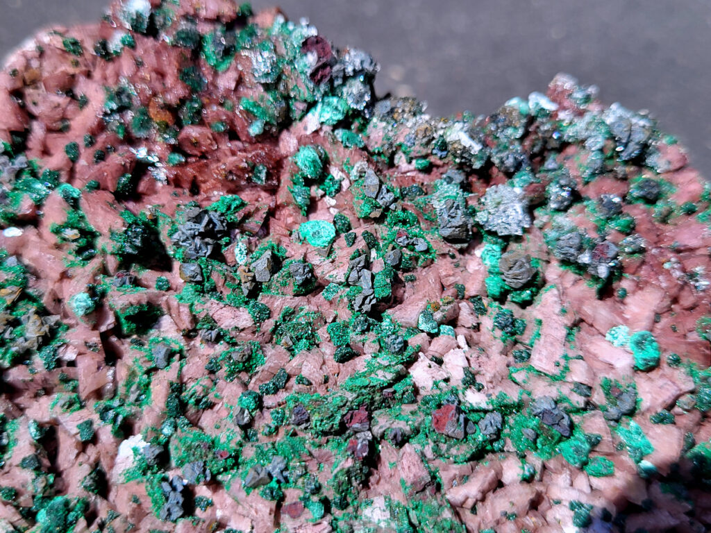 <strong>Malachiet op Dolemiet, 0,6kg, 14x10cm, 30,- euro, detailfoto, nr. 1

Malachiet op Dolomiet, beschrijving,
Dit kleurrijke exemplaar bevat blauwgroene rosasiet- en groene malachietkristallenaggregaties, bovenop een laag van donkerroodbruine ferroan dolomiet. Doorschijnende selenietkristallen zijn te vinden over de hele dolomiet, evenals die de rosasiet- en malachietkristalformaties omhullen.
Rosasiet is een secundair mineraal dat zich vormt in oxidatiezones van koper-zink afzettingen, waarbij doorgaans een vezelige botryoïdale bol ontstaat die glasachtig en zijdeachtig kan lijken. Hoewel ze doorgaans een blauwgroene kleur hebben, zijn kleurloze exemplaren niet ongehoord. De chemische formule van rosasiet is CuZnCO3(OH)2.

Over Malachiet:
Malachiet is een intens groen koperachtig mineraal dat in een grote verscheidenheid aan vormen voorkomt. Malachiet kan groeien in botryoïdale massa's, stalactietische formaties en reniforme formaties, meestal als een dichte cluster van waaierende vezelige naalden die een ogenschijnlijk vaste massa vormen. Naarmate lagen zich blijven opstapelen tijdens de vorming, kunnen soms gestreepte patronen vorm krijgen, wat de ringen in alle tinten groen verklaart die bij de meeste gepolijste malachietexemplaren te zien zijn.

Malachiet ontstaat door verwering van andere koperertsen en wordt zeer vaak gevonden in verband met andere koperhoudende mineralen zoals azuriet en chrysocolla. Het is te vinden in koperafzettingen over de hele wereld, maar de Democratische Republiek Congo is de belangrijkste bron voor gepolijste malachiet- en mineraalmonsters.

Malachiet wordt al sinds de oudheid gewaardeerd, eerst als utilitair kopererts en daarna als siersteen. Vanwege zijn waarde als decoratieve steen wordt het zelden nog als kopererts gewonnen.</strong>
