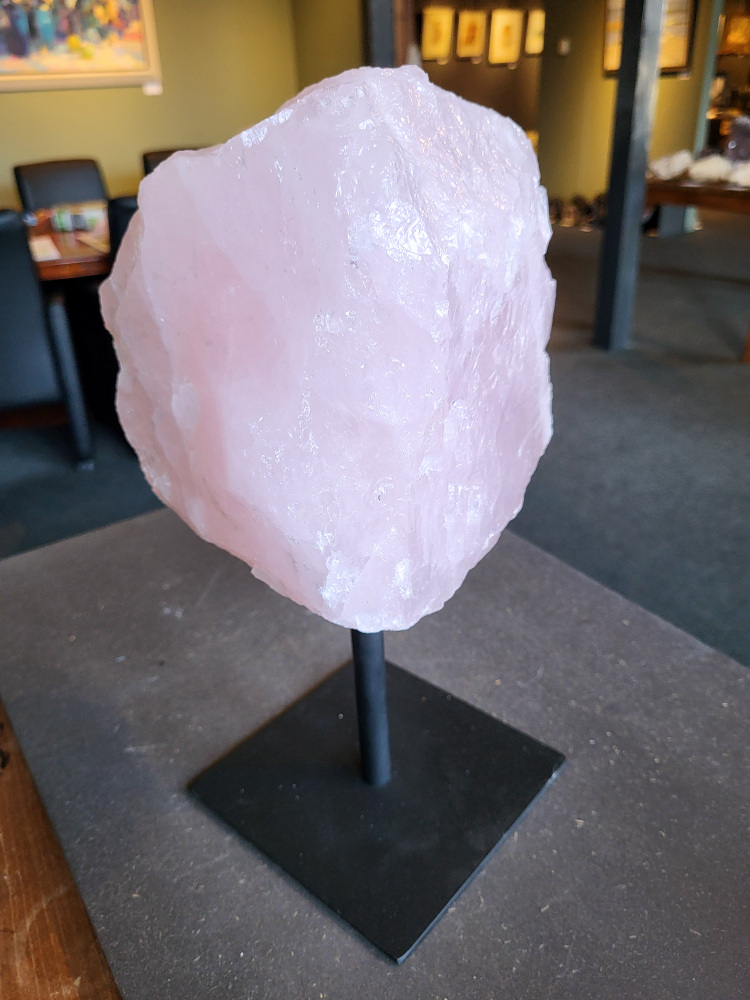Rozenkwarts op standaard, 7,8kg, 95,- euro, nr 23

Rozenkwarts, beschrijving
Rozenkwarts is een roze variëteit van kwarts, bekend om zijn zachte, liefdevolle energie en wordt vaak geassocieerd met het hartchakra.
Kenmerken:
Rozenkwarts varieert in kleur van lichtroze tot diep roze, vaak met een doorschijnende of troebele textuur.
Het is een mineraal dat voornamelijk bestaat uit siliciumdioxide, met sporen van titanium, ijzer of mangaan die de roze kleur veroorzaken.
Herkomst:
Rozenkwarts wordt op veel plaatsen in de wereld gevonden, waaronder Brazilië, Madagaskar, Rusland, India en de VS, maar de kwaliteit kan variëren.
Eigenschappen en Betekenis:

Rozenkwarts staat bekend als de "steen van de liefde" en wordt geassocieerd met het openen van het hartchakra, het bevorderen van zelfliefde, vergeving, compassie en het aantrekken van liefdevolle relaties.
Bescherming:
In sommige overtuigingen wordt rozenkwarts ook gebruikt voor bescherming en het afweren van negatieve energieën.
Verzorging:
Rozenkwarts kan het beste niet langdurig aan direct zonlicht worden blootgesteld, omdat de kleur kan vervagen.