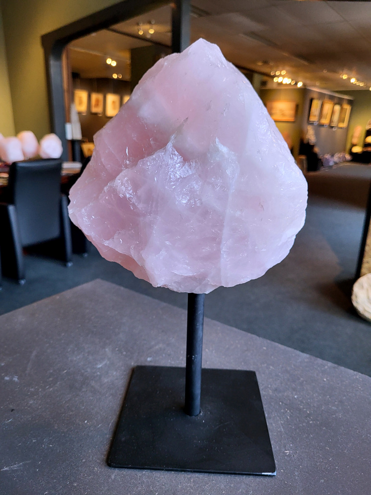 Rozenkwarts op standaard, 7kg, 85,- euro, nr. 24

Rozenkwarts, beschrijving
Rozenkwarts is een roze variëteit van kwarts, bekend om zijn zachte, liefdevolle energie en wordt vaak geassocieerd met het hartchakra.
Kenmerken:
Rozenkwarts varieert in kleur van lichtroze tot diep roze, vaak met een doorschijnende of troebele textuur.
Het is een mineraal dat voornamelijk bestaat uit siliciumdioxide, met sporen van titanium, ijzer of mangaan die de roze kleur veroorzaken.
Herkomst:
Rozenkwarts wordt op veel plaatsen in de wereld gevonden, waaronder Brazilië, Madagaskar, Rusland, India en de VS, maar de kwaliteit kan variëren.
Eigenschappen en Betekenis:

Rozenkwarts staat bekend als de "steen van de liefde" en wordt geassocieerd met het openen van het hartchakra, het bevorderen van zelfliefde, vergeving, compassie en het aantrekken van liefdevolle relaties.
Bescherming:
In sommige overtuigingen wordt rozenkwarts ook gebruikt voor bescherming en het afweren van negatieve energieën.
Verzorging:
Rozenkwarts kan het beste niet langdurig aan direct zonlicht worden blootgesteld, omdat de kleur kan vervagen.