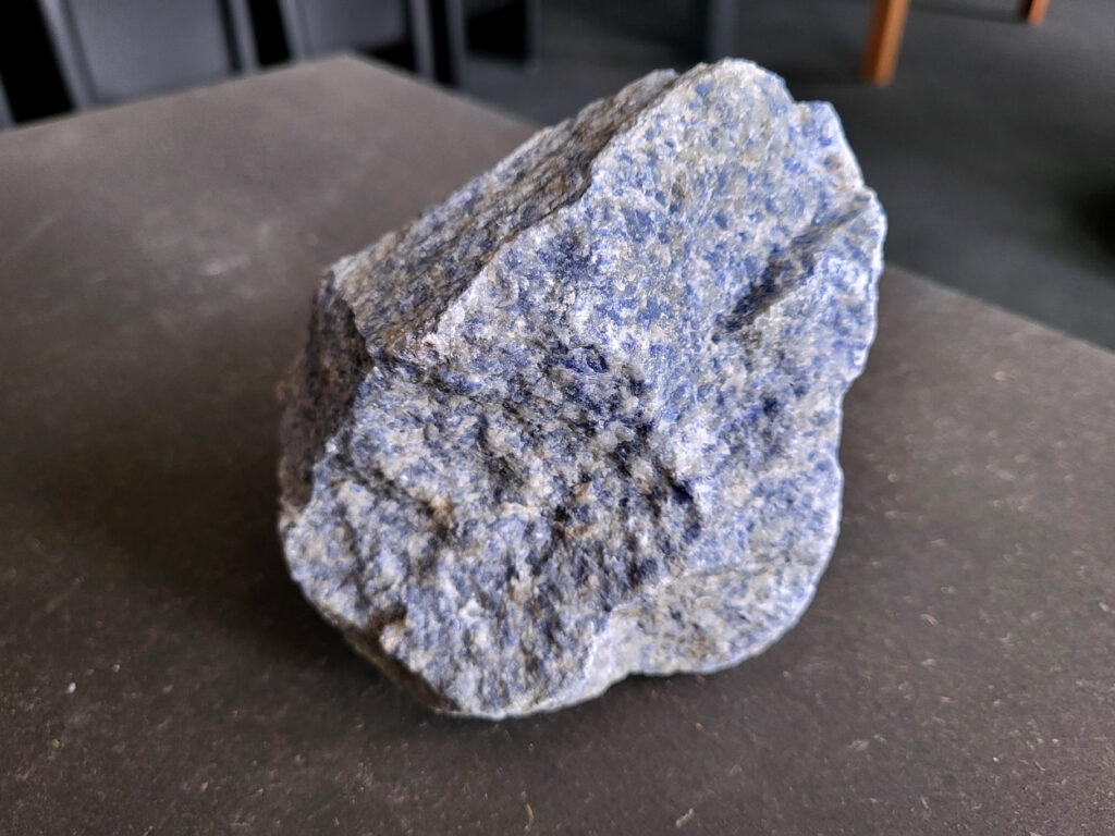 <strong>Sodaliet, ruw, 1,2kg, 9,- euro, nr. 14,

Sodaliet, beschrijving,
Sodaliet is een diepblauwe edelsteen en mineraal, bekend om zijn helderheid, spirituele betekenis en helende eigenschappen.
Sodaliet is een natrium-aluminiumsilicaat dat behoort tot de veldspaatmineralen en vaak witte aders of vlekken bevat, hoewel de mooiste kwaliteit inktblauw en zonder aders is (Sodaliet kan ook groen, rood of roze zijn afhankelijk van de samenstelling) . De steen heeft een hardheid van ongeveer 5,5–6 op de schaal van Mohs, een glasachtige tot matte glans en een gemiddelde dichtheid van 2,3–2,4 g/cm³. De naam sodaliet is afgeleid van het Engelse sodium (natrium) en het Griekse lithos (steen).  
Geschiedenis en gebruik
Sodaliet werd voor het eerst ontdekt in Zuid-Amerika, met name in Chili, en later ook in Brazilië en Uruguay. Het werd al snel populair als edelsteen en decoratief materiaal, gebruikt in sieraden, beeldjes, schalen en zelfs als blauwe verf of oogmake-up in de oudheid  Oude culturen zoals de Egyptenaren, Grieken en Romeinen waardeerden sodaliet om zijn beschermende en concentratie bevorderende eigenschappen . 
Spirituele en helende eigenschappen
Sodaliet staat bekend als de Steen van de Denker en wordt geassocieerd met rationaliteit, objectiviteit, intuïtie en innerlijke waarheid. Het helpt bij het structureren van gedachten, helder communiceren en zelfvertrouwen, en bevordert rust en focus tijdens werk, studie of meditatie  Spiritueel opent sodaliet het derde oogchakra, versterkt intuïtie en ondersteunt inzichtgevende meditaties. De steen wordt ook gebruikt om negatieve energie af te weren en harmonie in groepen te bevorderen. 
Fysieke voordelen
Fysiek kan sodaliet helpen bij keel-, hals- en stembandproblemen, het verlagen van bloeddruk, het ontspannen van nek en schouders, en het ondersteunen van het beenderstelsel en herstel van pezen  Dankzij het natriumgehalte heeft sodaliet ook een desinfecterende werking. 
Toepassingen
Sodaliet wordt vaak gebruikt in sieraden zoals kettingen, ringen en oorbellen, maar ook voor decoratieve objecten, houtsnijwerk en wandbedekking Het past goed bij de sterrenbeelden Boogschutter en Maagd, en kan helpen bij het vinden van focus, richting en zelfvertrouwen. 
Al met al is sodaliet een veelzijdige steen die zowel mentaal, emotioneel, fysiek als spiritueel ondersteuning biedt en geliefd is om zijn schoonheid en krachtige energetische eigenschappen.
</strong>