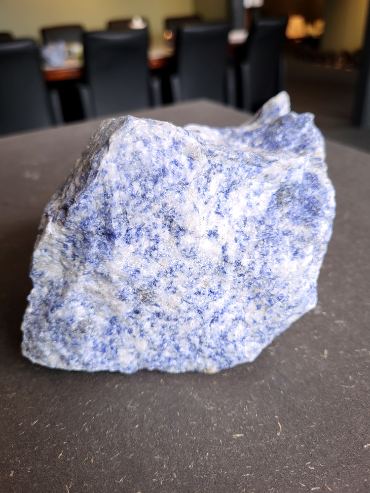<strong>Sodaliet, ruw, 1,3kg, 9,- euro, nr. 13,

Sodaliet, beschrijving,
Sodaliet is een diepblauwe edelsteen en mineraal, bekend om zijn helderheid, spirituele betekenis en helende eigenschappen.
Sodaliet is een natrium-aluminiumsilicaat dat behoort tot de veldspaatmineralen en vaak witte aders of vlekken bevat, hoewel de mooiste kwaliteit inktblauw en zonder aders is (Sodaliet kan ook groen, rood of roze zijn afhankelijk van de samenstelling) . De steen heeft een hardheid van ongeveer 5,5–6 op de schaal van Mohs, een glasachtige tot matte glans en een gemiddelde dichtheid van 2,3–2,4 g/cm³. De naam sodaliet is afgeleid van het Engelse sodium (natrium) en het Griekse lithos (steen).  
Geschiedenis en gebruik
Sodaliet werd voor het eerst ontdekt in Zuid-Amerika, met name in Chili, en later ook in Brazilië en Uruguay. Het werd al snel populair als edelsteen en decoratief materiaal, gebruikt in sieraden, beeldjes, schalen en zelfs als blauwe verf of oogmake-up in de oudheid  Oude culturen zoals de Egyptenaren, Grieken en Romeinen waardeerden sodaliet om zijn beschermende en concentratie bevorderende eigenschappen . 
Spirituele en helende eigenschappen
Sodaliet staat bekend als de Steen van de Denker en wordt geassocieerd met rationaliteit, objectiviteit, intuïtie en innerlijke waarheid. Het helpt bij het structureren van gedachten, helder communiceren en zelfvertrouwen, en bevordert rust en focus tijdens werk, studie of meditatie  Spiritueel opent sodaliet het derde oogchakra, versterkt intuïtie en ondersteunt inzichtgevende meditaties. De steen wordt ook gebruikt om negatieve energie af te weren en harmonie in groepen te bevorderen. 
Fysieke voordelen
Fysiek kan sodaliet helpen bij keel-, hals- en stembandproblemen, het verlagen van bloeddruk, het ontspannen van nek en schouders, en het ondersteunen van het beenderstelsel en herstel van pezen  Dankzij het natriumgehalte heeft sodaliet ook een desinfecterende werking. 
Toepassingen
Sodaliet wordt vaak gebruikt in sieraden zoals kettingen, ringen en oorbellen, maar ook voor decoratieve objecten, houtsnijwerk en wandbedekking Het past goed bij de sterrenbeelden Boogschutter en Maagd, en kan helpen bij het vinden van focus, richting en zelfvertrouwen. 
Al met al is sodaliet een veelzijdige steen die zowel mentaal, emotioneel, fysiek als spiritueel ondersteuning biedt en geliefd is om zijn schoonheid en krachtige energetische eigenschappen.</strong>