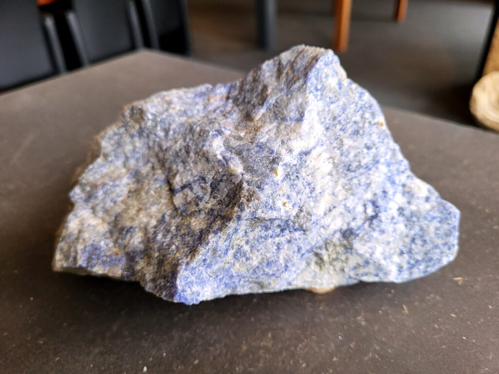 <strong>Sodaliet, ruw, 1,7 kg, 12,- euro, nr. 6

Sodaliet, beschrijving,
Sodaliet is een diepblauwe edelsteen en mineraal, bekend om zijn helderheid, spirituele betekenis en helende eigenschappen.
Sodaliet is een natrium-aluminiumsilicaat dat behoort tot de veldspaatmineralen en vaak witte aders of vlekken bevat, hoewel de mooiste kwaliteit inktblauw en zonder aders is (Sodaliet kan ook groen, rood of roze zijn afhankelijk van de samenstelling) . De steen heeft een hardheid van ongeveer 5,5–6 op de schaal van Mohs, een glasachtige tot matte glans en een gemiddelde dichtheid van 2,3–2,4 g/cm³. De naam sodaliet is afgeleid van het Engelse sodium (natrium) en het Griekse lithos (steen).  
Geschiedenis en gebruik
Sodaliet werd voor het eerst ontdekt in Zuid-Amerika, met name in Chili, en later ook in Brazilië en Uruguay. Het werd al snel populair als edelsteen en decoratief materiaal, gebruikt in sieraden, beeldjes, schalen en zelfs als blauwe verf of oogmake-up in de oudheid  Oude culturen zoals de Egyptenaren, Grieken en Romeinen waardeerden sodaliet om zijn beschermende en concentratie bevorderende eigenschappen . 
Spirituele en helende eigenschappen
Sodaliet staat bekend als de Steen van de Denker en wordt geassocieerd met rationaliteit, objectiviteit, intuïtie en innerlijke waarheid. Het helpt bij het structureren van gedachten, helder communiceren en zelfvertrouwen, en bevordert rust en focus tijdens werk, studie of meditatie  Spiritueel opent sodaliet het derde oogchakra, versterkt intuïtie en ondersteunt inzichtgevende meditaties. De steen wordt ook gebruikt om negatieve energie af te weren en harmonie in groepen te bevorderen. 
Fysieke voordelen
Fysiek kan sodaliet helpen bij keel-, hals- en stembandproblemen, het verlagen van bloeddruk, het ontspannen van nek en schouders, en het ondersteunen van het beenderstelsel en herstel van pezen  Dankzij het natriumgehalte heeft sodaliet ook een desinfecterende werking. 
Toepassingen
Sodaliet wordt vaak gebruikt in sieraden zoals kettingen, ringen en oorbellen, maar ook voor decoratieve objecten, houtsnijwerk en wandbedekking Het past goed bij de sterrenbeelden Boogschutter en Maagd, en kan helpen bij het vinden van focus, richting en zelfvertrouwen. 
Al met al is sodaliet een veelzijdige steen die zowel mentaal, emotioneel, fysiek als spiritueel ondersteuning biedt en geliefd is om zijn schoonheid en krachtige energetische eigenschappen.
</strong>