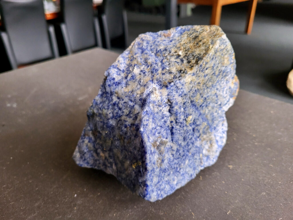 <strong>Sodaliet, ruw, 1,7 kg, 12,- euro, nr. 4

Sodaliet, beschrijving,
Sodaliet is een diepblauwe edelsteen en mineraal, bekend om zijn helderheid, spirituele betekenis en helende eigenschappen.
Sodaliet is een natrium-aluminiumsilicaat dat behoort tot de veldspaatmineralen en vaak witte aders of vlekken bevat, hoewel de mooiste kwaliteit inktblauw en zonder aders is (Sodaliet kan ook groen, rood of roze zijn afhankelijk van de samenstelling) . De steen heeft een hardheid van ongeveer 5,5–6 op de schaal van Mohs, een glasachtige tot matte glans en een gemiddelde dichtheid van 2,3–2,4 g/cm³. De naam sodaliet is afgeleid van het Engelse sodium (natrium) en het Griekse lithos (steen).  
Geschiedenis en gebruik
Sodaliet werd voor het eerst ontdekt in Zuid-Amerika, met name in Chili, en later ook in Brazilië en Uruguay. Het werd al snel populair als edelsteen en decoratief materiaal, gebruikt in sieraden, beeldjes, schalen en zelfs als blauwe verf of oogmake-up in de oudheid  Oude culturen zoals de Egyptenaren, Grieken en Romeinen waardeerden sodaliet om zijn beschermende en concentratie bevorderende eigenschappen . 
Spirituele en helende eigenschappen
Sodaliet staat bekend als de Steen van de Denker en wordt geassocieerd met rationaliteit, objectiviteit, intuïtie en innerlijke waarheid. Het helpt bij het structureren van gedachten, helder communiceren en zelfvertrouwen, en bevordert rust en focus tijdens werk, studie of meditatie  Spiritueel opent sodaliet het derde oogchakra, versterkt intuïtie en ondersteunt inzichtgevende meditaties. De steen wordt ook gebruikt om negatieve energie af te weren en harmonie in groepen te bevorderen. 
Fysieke voordelen
Fysiek kan sodaliet helpen bij keel-, hals- en stembandproblemen, het verlagen van bloeddruk, het ontspannen van nek en schouders, en het ondersteunen van het beenderstelsel en herstel van pezen  Dankzij het natriumgehalte heeft sodaliet ook een desinfecterende werking. 
Toepassingen
Sodaliet wordt vaak gebruikt in sieraden zoals kettingen, ringen en oorbellen, maar ook voor decoratieve objecten, houtsnijwerk en wandbedekking Het past goed bij de sterrenbeelden Boogschutter en Maagd, en kan helpen bij het vinden van focus, richting en zelfvertrouwen. 
Al met al is sodaliet een veelzijdige steen die zowel mentaal, emotioneel, fysiek als spiritueel ondersteuning biedt en geliefd is om zijn schoonheid en krachtige energetische eigenschappen.
</strong>