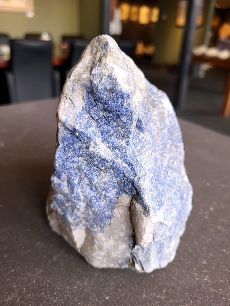 <strong>Sodaliet, ruw, 1,7 kg, 12,- euro, nr. 10,

Sodaliet, beschrijving,
Sodaliet is een diepblauwe edelsteen en mineraal, bekend om zijn helderheid, spirituele betekenis en helende eigenschappen.
Sodaliet is een natrium-aluminiumsilicaat dat behoort tot de veldspaatmineralen en vaak witte aders of vlekken bevat, hoewel de mooiste kwaliteit inktblauw en zonder aders is (Sodaliet kan ook groen, rood of roze zijn afhankelijk van de samenstelling) . De steen heeft een hardheid van ongeveer 5,5–6 op de schaal van Mohs, een glasachtige tot matte glans en een gemiddelde dichtheid van 2,3–2,4 g/cm³. De naam sodaliet is afgeleid van het Engelse sodium (natrium) en het Griekse lithos (steen).  
Geschiedenis en gebruik
Sodaliet werd voor het eerst ontdekt in Zuid-Amerika, met name in Chili, en later ook in Brazilië en Uruguay. Het werd al snel populair als edelsteen en decoratief materiaal, gebruikt in sieraden, beeldjes, schalen en zelfs als blauwe verf of oogmake-up in de oudheid  Oude culturen zoals de Egyptenaren, Grieken en Romeinen waardeerden sodaliet om zijn beschermende en concentratie bevorderende eigenschappen . 
Spirituele en helende eigenschappen
Sodaliet staat bekend als de Steen van de Denker en wordt geassocieerd met rationaliteit, objectiviteit, intuïtie en innerlijke waarheid. Het helpt bij het structureren van gedachten, helder communiceren en zelfvertrouwen, en bevordert rust en focus tijdens werk, studie of meditatie  Spiritueel opent sodaliet het derde oogchakra, versterkt intuïtie en ondersteunt inzichtgevende meditaties. De steen wordt ook gebruikt om negatieve energie af te weren en harmonie in groepen te bevorderen. 
Fysieke voordelen
Fysiek kan sodaliet helpen bij keel-, hals- en stembandproblemen, het verlagen van bloeddruk, het ontspannen van nek en schouders, en het ondersteunen van het beenderstelsel en herstel van pezen  Dankzij het natriumgehalte heeft sodaliet ook een desinfecterende werking. 
Toepassingen
Sodaliet wordt vaak gebruikt in sieraden zoals kettingen, ringen en oorbellen, maar ook voor decoratieve objecten, houtsnijwerk en wandbedekking Het past goed bij de sterrenbeelden Boogschutter en Maagd, en kan helpen bij het vinden van focus, richting en zelfvertrouwen. 
Al met al is sodaliet een veelzijdige steen die zowel mentaal, emotioneel, fysiek als spiritueel ondersteuning biedt en geliefd is om zijn schoonheid en krachtige energetische eigenschappen.
</strong>