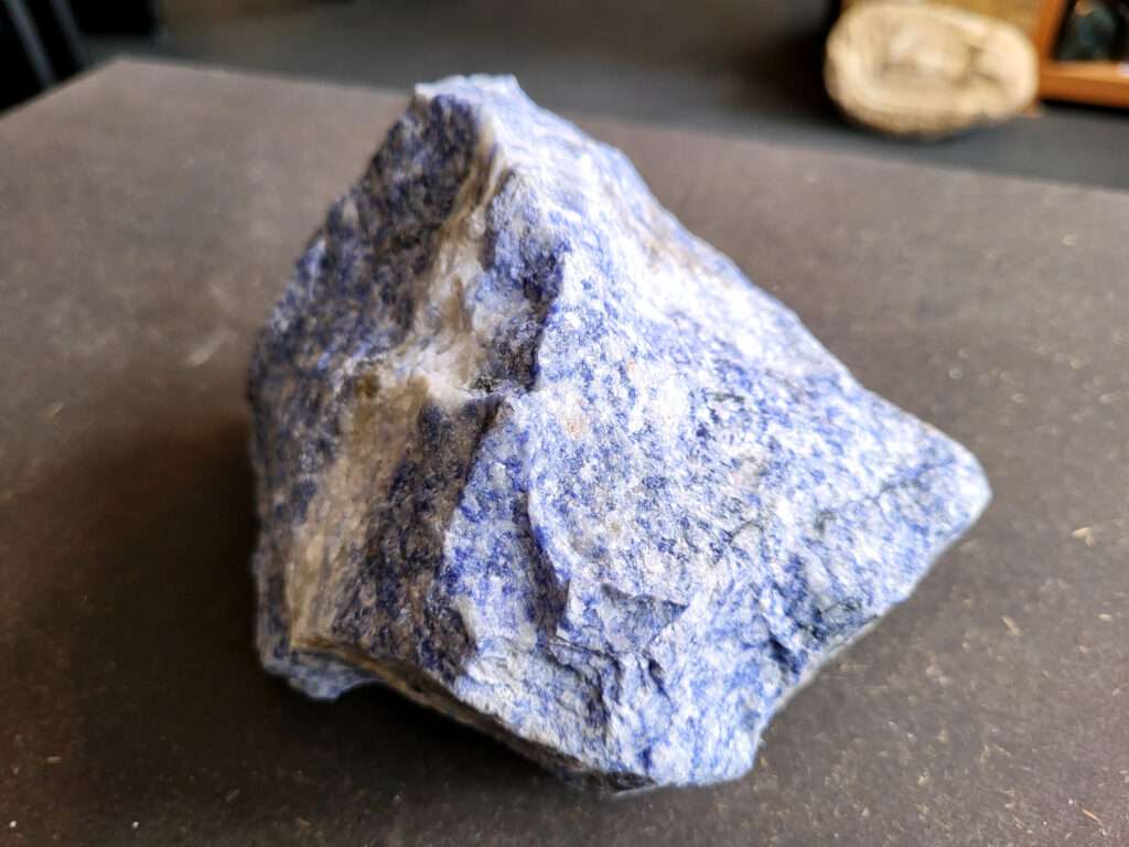 <strong>Sodaliet, ruw, 1,8 kg, 13,- euro, nr. 3

Sodaliet, beschrijving,
Sodaliet is een diepblauwe edelsteen en mineraal, bekend om zijn helderheid, spirituele betekenis en helende eigenschappen.
Sodaliet is een natrium-aluminiumsilicaat dat behoort tot de veldspaatmineralen en vaak witte aders of vlekken bevat, hoewel de mooiste kwaliteit inktblauw en zonder aders is (Sodaliet kan ook groen, rood of roze zijn afhankelijk van de samenstelling) . De steen heeft een hardheid van ongeveer 5,5–6 op de schaal van Mohs, een glasachtige tot matte glans en een gemiddelde dichtheid van 2,3–2,4 g/cm³. De naam sodaliet is afgeleid van het Engelse sodium (natrium) en het Griekse lithos (steen).  
Geschiedenis en gebruik
Sodaliet werd voor het eerst ontdekt in Zuid-Amerika, met name in Chili, en later ook in Brazilië en Uruguay. Het werd al snel populair als edelsteen en decoratief materiaal, gebruikt in sieraden, beeldjes, schalen en zelfs als blauwe verf of oogmake-up in de oudheid  Oude culturen zoals de Egyptenaren, Grieken en Romeinen waardeerden sodaliet om zijn beschermende en concentratie bevorderende eigenschappen . 
Spirituele en helende eigenschappen
Sodaliet staat bekend als de Steen van de Denker en wordt geassocieerd met rationaliteit, objectiviteit, intuïtie en innerlijke waarheid. Het helpt bij het structureren van gedachten, helder communiceren en zelfvertrouwen, en bevordert rust en focus tijdens werk, studie of meditatie  Spiritueel opent sodaliet het derde oogchakra, versterkt intuïtie en ondersteunt inzichtgevende meditaties. De steen wordt ook gebruikt om negatieve energie af te weren en harmonie in groepen te bevorderen. 
Fysieke voordelen
Fysiek kan sodaliet helpen bij keel-, hals- en stembandproblemen, het verlagen van bloeddruk, het ontspannen van nek en schouders, en het ondersteunen van het beenderstelsel en herstel van pezen  Dankzij het natriumgehalte heeft sodaliet ook een desinfecterende werking. 
Toepassingen
Sodaliet wordt vaak gebruikt in sieraden zoals kettingen, ringen en oorbellen, maar ook voor decoratieve objecten, houtsnijwerk en wandbedekking Het past goed bij de sterrenbeelden Boogschutter en Maagd, en kan helpen bij het vinden van focus, richting en zelfvertrouwen. 
Al met al is sodaliet een veelzijdige steen die zowel mentaal, emotioneel, fysiek als spiritueel ondersteuning biedt en geliefd is om zijn schoonheid en krachtige energetische eigenschappen.
</strong>