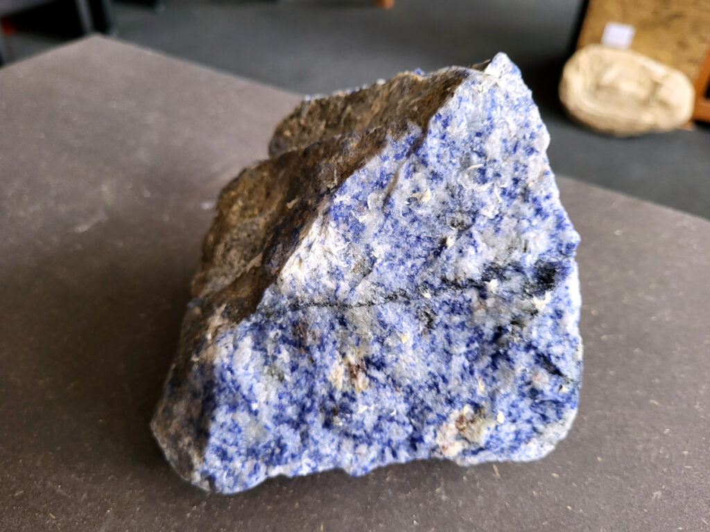 <strong>Sodaliet, ruw, 1,8kg, 13,- euro, nr. 2

Sodaliet, beschrijving,
Sodaliet is een diepblauwe edelsteen en mineraal, bekend om zijn helderheid, spirituele betekenis en helende eigenschappen.
Sodaliet is een natrium-aluminiumsilicaat dat behoort tot de veldspaatmineralen en vaak witte aders of vlekken bevat, hoewel de mooiste kwaliteit inktblauw en zonder aders is (Sodaliet kan ook groen, rood of roze zijn afhankelijk van de samenstelling) . De steen heeft een hardheid van ongeveer 5,5–6 op de schaal van Mohs, een glasachtige tot matte glans en een gemiddelde dichtheid van 2,3–2,4 g/cm³. De naam sodaliet is afgeleid van het Engelse sodium (natrium) en het Griekse lithos (steen).  
Geschiedenis en gebruik
Sodaliet werd voor het eerst ontdekt in Zuid-Amerika, met name in Chili, en later ook in Brazilië en Uruguay. Het werd al snel populair als edelsteen en decoratief materiaal, gebruikt in sieraden, beeldjes, schalen en zelfs als blauwe verf of oogmake-up in de oudheid  Oude culturen zoals de Egyptenaren, Grieken en Romeinen waardeerden sodaliet om zijn beschermende en concentratie bevorderende eigenschappen . 
Spirituele en helende eigenschappen
Sodaliet staat bekend als de Steen van de Denker en wordt geassocieerd met rationaliteit, objectiviteit, intuïtie en innerlijke waarheid. Het helpt bij het structureren van gedachten, helder communiceren en zelfvertrouwen, en bevordert rust en focus tijdens werk, studie of meditatie  Spiritueel opent sodaliet het derde oogchakra, versterkt intuïtie en ondersteunt inzichtgevende meditaties. De steen wordt ook gebruikt om negatieve energie af te weren en harmonie in groepen te bevorderen. 
Fysieke voordelen
Fysiek kan sodaliet helpen bij keel-, hals- en stembandproblemen, het verlagen van bloeddruk, het ontspannen van nek en schouders, en het ondersteunen van het beenderstelsel en herstel van pezen  Dankzij het natriumgehalte heeft sodaliet ook een desinfecterende werking. 
Toepassingen
Sodaliet wordt vaak gebruikt in sieraden zoals kettingen, ringen en oorbellen, maar ook voor decoratieve objecten, houtsnijwerk en wandbedekking Het past goed bij de sterrenbeelden Boogschutter en Maagd, en kan helpen bij het vinden van focus, richting en zelfvertrouwen. 
Al met al is sodaliet een veelzijdige steen die zowel mentaal, emotioneel, fysiek als spiritueel ondersteuning biedt en geliefd is om zijn schoonheid en krachtige energetische eigenschappen.
</strong>