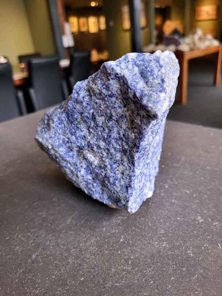 <strong>Sodaliet, ruw, 2 kg, 14,- euro, nr. 9,

Sodaliet, beschrijving,
Sodaliet is een diepblauwe edelsteen en mineraal, bekend om zijn helderheid, spirituele betekenis en helende eigenschappen.
Sodaliet is een natrium-aluminiumsilicaat dat behoort tot de veldspaatmineralen en vaak witte aders of vlekken bevat, hoewel de mooiste kwaliteit inktblauw en zonder aders is (Sodaliet kan ook groen, rood of roze zijn afhankelijk van de samenstelling) . De steen heeft een hardheid van ongeveer 5,5–6 op de schaal van Mohs, een glasachtige tot matte glans en een gemiddelde dichtheid van 2,3–2,4 g/cm³. De naam sodaliet is afgeleid van het Engelse sodium (natrium) en het Griekse lithos (steen).  
Geschiedenis en gebruik
Sodaliet werd voor het eerst ontdekt in Zuid-Amerika, met name in Chili, en later ook in Brazilië en Uruguay. Het werd al snel populair als edelsteen en decoratief materiaal, gebruikt in sieraden, beeldjes, schalen en zelfs als blauwe verf of oogmake-up in de oudheid  Oude culturen zoals de Egyptenaren, Grieken en Romeinen waardeerden sodaliet om zijn beschermende en concentratie bevorderende eigenschappen . 
Spirituele en helende eigenschappen
Sodaliet staat bekend als de Steen van de Denker en wordt geassocieerd met rationaliteit, objectiviteit, intuïtie en innerlijke waarheid. Het helpt bij het structureren van gedachten, helder communiceren en zelfvertrouwen, en bevordert rust en focus tijdens werk, studie of meditatie  Spiritueel opent sodaliet het derde oogchakra, versterkt intuïtie en ondersteunt inzichtgevende meditaties. De steen wordt ook gebruikt om negatieve energie af te weren en harmonie in groepen te bevorderen. 
Fysieke voordelen
Fysiek kan sodaliet helpen bij keel-, hals- en stembandproblemen, het verlagen van bloeddruk, het ontspannen van nek en schouders, en het ondersteunen van het beenderstelsel en herstel van pezen  Dankzij het natriumgehalte heeft sodaliet ook een desinfecterende werking. 
Toepassingen
Sodaliet wordt vaak gebruikt in sieraden zoals kettingen, ringen en oorbellen, maar ook voor decoratieve objecten, houtsnijwerk en wandbedekking Het past goed bij de sterrenbeelden Boogschutter en Maagd, en kan helpen bij het vinden van focus, richting en zelfvertrouwen. 
Al met al is sodaliet een veelzijdige steen die zowel mentaal, emotioneel, fysiek als spiritueel ondersteuning biedt en geliefd is om zijn schoonheid en krachtige energetische eigenschappen.
</strong>