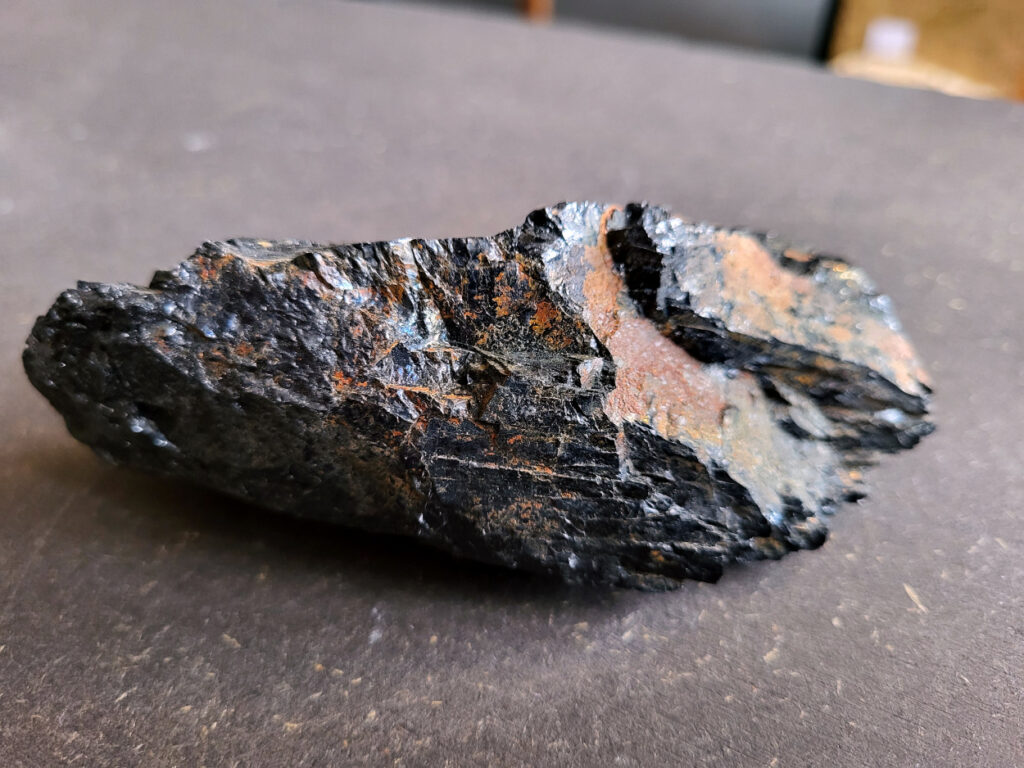 <strong>Toermalijn, zwarte toermalijn, 12,- euro, nr. 2

Zwarte toermalijn, beschrijving
Zwarte toermalijn (schorl) in een veldspaat-matrix.
Zwarte deel: zwarte toermalijn (schorl)
Bruin/roze gesteente eromheen: veldspaat (vaak kaliveldspaat uit pegmatiet)
Herkenningspunten
Zwart kristal met duidelijke lengtestrepen / lijnen
Vaak prismatisch (langwerpig kristal)
Zit vaak ingegroeid in veldspaat of granietachtige steen
Komt veel voor in pegmatietgesteente
Dit soort stukken ontstaan diep in de aarde wanneer magma langzaam afkoelt. In pegmatieten kunnen dan grote kristallen groeien, zoals:
Veldspaat, kwarts en toermalijn
Zwarte Toermalijn in Veldspaat
Zwarte toermalijn in veldspaat combineert de aardende en beschermende eigenschappen van zwarte toermalijn met de harmoniserende energieën van veldspaat. Deze unieke steen wordt gevormd wanneer zwarte toermalijnkristallen op natuurlijke wijze zijn ingebed in de veldspaatmatrix, waardoor een opvallend contrast ontstaat tussen de donkere toermalijn en de lichtere veldspaat.
Zwarte toermalijn staat bekend om zijn vermogen om negatieve energieën te absorberen en psychische bescherming te bieden. Het fungeert als een schild, buigt schadelijke energieën af en bevordert een gevoel van veiligheid en zekerheid. Met zijn aardende eigenschappen helpt zwarte toermalijn de drager te verankeren in de aarde, waardoor een gevoel van stabiliteit en evenwicht wordt bevorderd.
Veldspaat daarentegen is een steen van harmonie en integratie. Het bevordert een gevoel van eenheid en samenwerking, zowel binnen jezelf als in relaties met anderen. Veldspaat staat ook bekend om zijn kalmerende en verzachtende eigenschappen, waardoor stress en angst worden verlicht.
Samen creëert zwarte toermalijn in veldspaat een krachtige synergie van energieën. Het dient als een krachtig hulpmiddel voor spirituele bescherming en aarding, terwijl het ook innerlijke harmonie en emotioneel evenwicht bevordert. Deze steen kan bijzonder nuttig zijn voor degenen die een gevoel van stabiliteit en veiligheid in hun leven willen creëren, terwijl ze ook een diepere verbinding met de aarde en het spirituele rijk bevorderen.</strong>