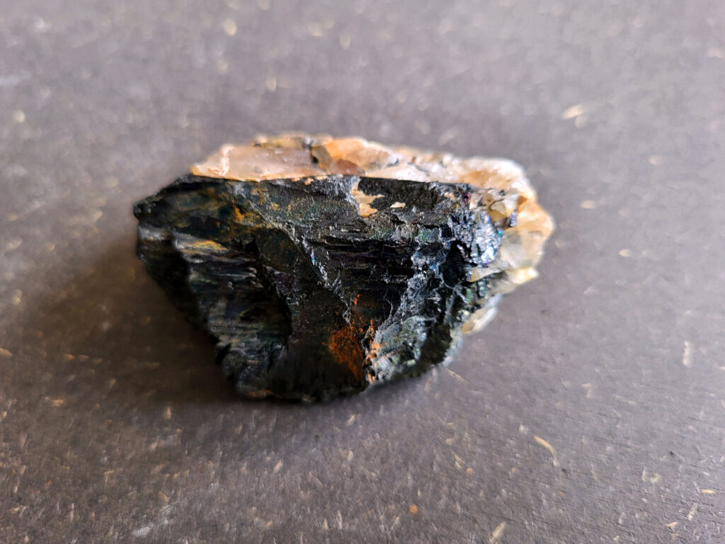Toermalijn, zwarte toermalijn, 4,- euro, nr. 1

<strong>Zwarte toermalijn, beschrijving
Zwarte toermalijn (schorl) in een veldspaat-matrix.
Zwarte deel: zwarte toermalijn (schorl)
Bruin/roze gesteente eromheen: veldspaat (vaak kaliveldspaat uit pegmatiet)
Herkenningspunten
Zwart kristal met duidelijke lengtestrepen / lijnen
Vaak prismatisch (langwerpig kristal)
Zit vaak ingegroeid in veldspaat of granietachtige steen
Komt veel voor in pegmatietgesteente
Dit soort stukken ontstaan diep in de aarde wanneer magma langzaam afkoelt. In pegmatieten kunnen dan grote kristallen groeien, zoals:
Veldspaat, kwarts en toermalijn
Zwarte Toermalijn in Veldspaat
Zwarte toermalijn in veldspaat combineert de aardende en beschermende eigenschappen van zwarte toermalijn met de harmoniserende energieën van veldspaat. Deze unieke steen wordt gevormd wanneer zwarte toermalijnkristallen op natuurlijke wijze zijn ingebed in de veldspaatmatrix, waardoor een opvallend contrast ontstaat tussen de donkere toermalijn en de lichtere veldspaat.
Zwarte toermalijn staat bekend om zijn vermogen om negatieve energieën te absorberen en psychische bescherming te bieden. Het fungeert als een schild, buigt schadelijke energieën af en bevordert een gevoel van veiligheid en zekerheid. Met zijn aardende eigenschappen helpt zwarte toermalijn de drager te verankeren in de aarde, waardoor een gevoel van stabiliteit en evenwicht wordt bevorderd.
Veldspaat daarentegen is een steen van harmonie en integratie. Het bevordert een gevoel van eenheid en samenwerking, zowel binnen jezelf als in relaties met anderen. Veldspaat staat ook bekend om zijn kalmerende en verzachtende eigenschappen, waardoor stress en angst worden verlicht.
Samen creëert zwarte toermalijn in veldspaat een krachtige synergie van energieën. Het dient als een krachtig hulpmiddel voor spirituele bescherming en aarding, terwijl het ook innerlijke harmonie en emotioneel evenwicht bevordert. Deze steen kan bijzonder nuttig zijn voor degenen die een gevoel van stabiliteit en veiligheid in hun leven willen creëren, terwijl ze ook een diepere verbinding met de aarde en het spirituele rijk bevorderen.</strong>