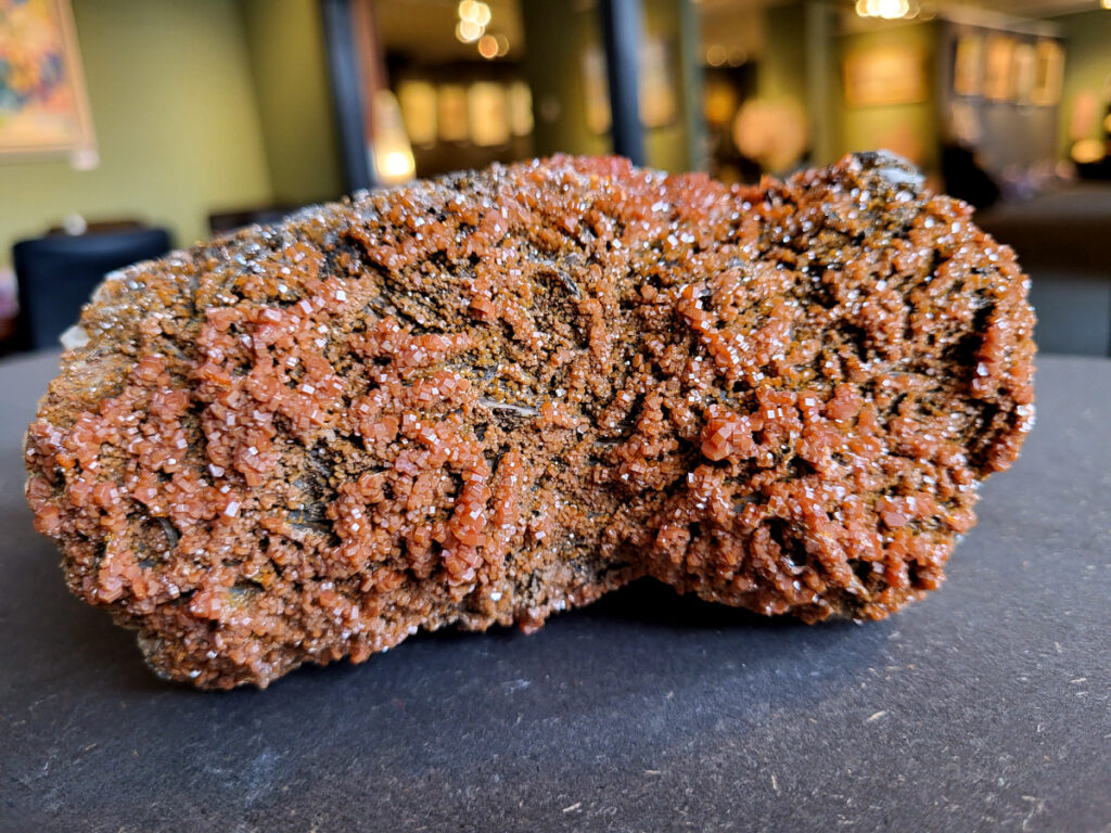 <strong>Vanadiniet op Bariet, 2,5 kg, doorsnee 18cm, 125,- euro, nr. 101</strong>

<strong>Vanadiniet, beschrijving,</strong>

Vanadiniet is een mineraal behorend tot de groep van chlooride mineralen van lood (Pb₅(VO₄)₃Cl). Het staat bekend om zijn dieprode tot oranjerode    kristallen, vaak hexagonaal van vorm. Vanadiniet ontstaat meestal in de     oxidatiezone van loodertsen, en het wordt soms verzameld vanwege zijn spectaculaire kristalvorm en kleur. Vanadiniet kan ook geringe hoeveelheden bariet en andere achtergrondmineralen bevatten. Het heeft een hoge           densiteit en een glasachtige glans.

<strong>Associatie van Vanadiniet met Bariet</strong>
In de minerologie komt vanadiniet vaak voor op of samen met bariet, 
omdat beide mineralen zich kunnen vormen in de oxidatiezone van 
loodaders. Deze combinatie wordt soms door verzamelaars gezocht omdat de contrasterende kleuren en kristalvormen esthetisch aantrekkelijk zijn: de rode kristallen van vanadiniet op een witte of lichtgekleurde barietbasis. Van bijzondere exemplaren wordt er een hogere verzamelwaarde gegeven.
Vindplaatsen
<strong>Vanadiniet met bariet wordt gevonden in meerdere locaties wereldwijd, </strong>
vooral in gebieden met lood- en zinkaders in woestijnachtige of rotsachtige omgevingen. Bekende vindplaatsen zijn Mexico, Marokko en sommige 
delen van de Verenigde Staten, waar vanadiniet op barietplaten in 
oxidatiezones wordt aangetroffen.

<strong>Gebruik en Verzamelwaarde
Verzamelaars: Vanadiniet-op-bariet specimens zijn populair vanwege de visuele aantrekkingskracht.</strong>
Wetenschappelijk: Beide mineralen zijn interessant voor studie van oxidatieprocessen en geochemie van zware metalen.
Industrieel: Bariet is industrieel belangrijk; vanadiniet heeft zeldzaam een kleine toepassing als vanadiumbron, maar vooral verzamelobject.
Kortom, vanadiniet op bariet is een aantrekkelijke combinatie voor mineralenverzamelaars en geeft inzicht in geologische processen in oxidatiezones van loodaders.