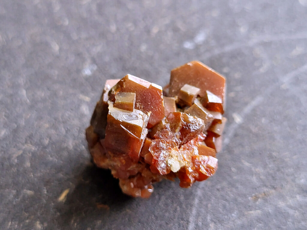 <strong>Vanadiniet, 2cm doorsnee, 10,- euro, nr. 114

Vanadiniet, beschrijving,

Vanadiniet is een mineraal behorend tot de groep van chlooride mineralen van lood (Pb₅(VO₄)₃Cl). Het staat bekend om zijn dieprode tot oranjerode    kristallen, vaak hexagonaal van vorm. Vanadiniet ontstaat meestal in de     oxidatiezone van loodertsen, en het wordt soms verzameld vanwege zijn spectaculaire kristalvorm en kleur. Vanadiniet kan ook geringe hoeveelheden bariet en andere achtergrondmineralen bevatten. Het heeft een hoge           densiteit en een glasachtige glans.

Associatie van Vanadiniet met Bariet
In de minerologie komt vanadiniet vaak voor op of samen met bariet, 
omdat beide mineralen zich kunnen vormen in de oxidatiezone van 
loodaders. Deze combinatie wordt soms door verzamelaars gezocht omdat de contrasterende kleuren en kristalvormen esthetisch aantrekkelijk zijn: de rode kristallen van vanadiniet op een witte of lichtgekleurde barietbasis. Van bijzondere exemplaren wordt er een hogere verzamelwaarde gegeven.
Vindplaatsen
Vanadiniet met bariet wordt gevonden in meerdere locaties wereldwijd, 
vooral in gebieden met lood- en zinkaders in woestijnachtige of rotsachtige omgevingen. Bekende vindplaatsen zijn Mexico, Marokko en sommige 
delen van de Verenigde Staten, waar vanadiniet op barietplaten in 
oxidatiezones wordt aangetroffen.

Gebruik en Verzamelwaarde
Verzamelaars: Vanadiniet-op-bariet specimens zijn populair vanwege de visuele aantrekkingskracht.
Wetenschappelijk: Beide mineralen zijn interessant voor studie van oxidatieprocessen en geochemie van zware metalen.
Industrieel: Bariet is industrieel belangrijk; vanadiniet heeft zeldzaam een kleine toepassing als vanadiumbron, maar vooral verzamelobject.
Kortom, vanadiniet op bariet is een aantrekkelijke combinatie voor mineralenverzamelaars en geeft inzicht in geologische processen in oxidatiezones van loodaders.
</strong>