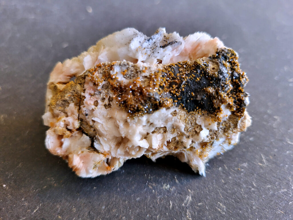 <strong>Vanadiniet op Bariet, 118 gram, 6cm doorsnee, 8,- euro, nr. 121

Vanadiniet, beschrijving,

Vanadiniet is een mineraal behorend tot de groep van chlooride mineralen van lood (Pb₅(VO₄)₃Cl). Het staat bekend om zijn dieprode tot oranjerode    kristallen, vaak hexagonaal van vorm. Vanadiniet ontstaat meestal in de     oxidatiezone van loodertsen, en het wordt soms verzameld vanwege zijn spectaculaire kristalvorm en kleur. Vanadiniet kan ook geringe hoeveelheden bariet en andere achtergrondmineralen bevatten. Het heeft een hoge           densiteit en een glasachtige glans.

Associatie van Vanadiniet met Bariet
In de minerologie komt vanadiniet vaak voor op of samen met bariet, 
omdat beide mineralen zich kunnen vormen in de oxidatiezone van 
loodaders. Deze combinatie wordt soms door verzamelaars gezocht omdat de contrasterende kleuren en kristalvormen esthetisch aantrekkelijk zijn: de rode kristallen van vanadiniet op een witte of lichtgekleurde barietbasis. Van bijzondere exemplaren wordt er een hogere verzamelwaarde gegeven.
Vindplaatsen
Vanadiniet met bariet wordt gevonden in meerdere locaties wereldwijd, 
vooral in gebieden met lood- en zinkaders in woestijnachtige of rotsachtige omgevingen. Bekende vindplaatsen zijn Mexico, Marokko en sommige 
delen van de Verenigde Staten, waar vanadiniet op barietplaten in 
oxidatiezones wordt aangetroffen.

Gebruik en Verzamelwaarde
Verzamelaars: Vanadiniet-op-bariet specimens zijn populair vanwege de visuele aantrekkingskracht.
Wetenschappelijk: Beide mineralen zijn interessant voor studie van oxidatieprocessen en geochemie van zware metalen.
Industrieel: Bariet is industrieel belangrijk; vanadiniet heeft zeldzaam een kleine toepassing als vanadiumbron, maar vooral verzamelobject.
Kortom, vanadiniet op bariet is een aantrekkelijke combinatie voor mineralenverzamelaars en geeft inzicht in geologische processen in oxidatiezones van loodaders.
</strong>