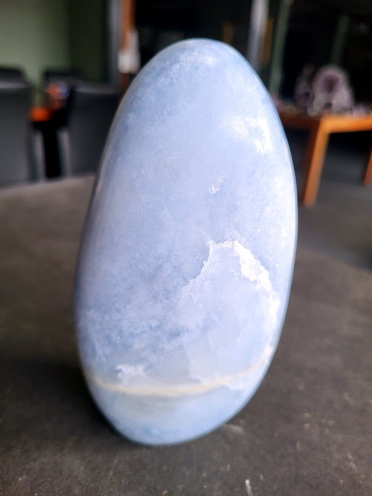 Blauwe Calciet sculptuur, 1 kg, 16 euro, nr. 50

Calciet, 
Calciet is een veelvoorkomend mineraal dat voornamelijk bestaat uit calciumcarbonaat. Het komt in diverse kleuren en vormen voor en wordt in veel industrieën gebruikt, maar ook in de esoterie.
Algemene kenmerken:
Samenstelling: Calciet bestaat voornamelijk uit calciumcarbonaat (CaCO3).
Vorming: Het ontstaat door afzetting van calciumcarbonaat in water, maar ook door ophoping van schelpen en skeletten van zeedieren.
Uiterlijk: Het heeft vaak een glasachtige glans, is doorzichtig tot doorschijnend en kan vele kleuren hebben, zoals geel, oranje, rood, bruin, blauw, groen, roze, wit en kleurloos.
Hardheid: Calciet heeft een hardheid van 3 op de schaal van Mohs.
Veelvoorkomend: Het is een van de meest voorkomende mineralen en is een hoofdbestanddeel van kalksteen, marmer en krijt.
Esoterie:
In de edelsteentherapie wordt calciet gezien als een steen die energie versterkt, negatieve energieën verwijdert en spirituele groei bevordert. Verschillende kleuren calciet hebben specifieke eigenschappen, zoals gele calciet voor doorzettingsvermogen en moed, en mangano calciet voor emotionele heling.
Specifieke calcietsoorten:
Gele Calciet: Staat bekend om het absorberen van negativiteit, het versterken van doorzettingsvermogen en het aantrekken van succes.
Blauwe Calciet: Wordt geassocieerd met kalmering, communicatie en het loslaten van stress.
Groene Calciet: Werkt op de hartchakra, bevordert liefde, compassie en emotionele heling.
Mangano Calciet: Wordt gebruikt voor emotionele heling, het loslaten van oud verdriet en het versterken van zelfvertrouwen.
Reiniging:
Calciet kan op verschillende manieren gereinigd worden, maar het is belangrijk om te weten dat sommige soorten, zoals gele calciet, niet goed tegen water kunnen.
Andere reinigingsmethoden zijn bijvoorbeeld reinigen met edelstenenspray, op een Amethist of bergkristal leggen, of reinigen met selenite.
Het is een steen die kan worden gebruikt voor energieversterking, emotionele heling en het bevorderen van spirituele groei, afhankelijk van de specifieke kleur en eigenschappen.
-Kunstgalerie Arnold-