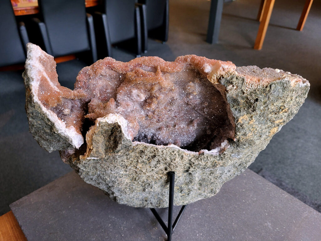 Chalcedoon met druzy kristallen, 6kg, 275 euro, foto voorkant, nr. 1

Chalcedoon geode met druzy kristallen.
Geodes ontstaan in holtes van gesteente (vaak vulkanisch). Mineralenrijk water vult die holte en kristalliseert langzaam, waardoor die fijne kristalletjes groeien.

De buitenkant is ruw en gesteente achtig, dat is de “schil” van de geode.
Binnenin zit een holte en dat is typisch voor een geode.
De binnenkant is bedekt met kleine, glinsterende kristalletjes en dat noem je druzy (druze).
De lichtblauwe/groene tint wijst op chalcedoon, een microkristallijne vorm van kwarts.
Kenmerken:
Materiaal: chalcedoon (kwartsfamilie)
Structuur: geode met druzy coating
Kleur: wit tot licht blauw/groen
Glans: suikerachtig, sprankelend

Vergelijkbaar met:
Agaat-geodes (maar die hebben vaak duidelijke banden)
Kwarts-geodes (meestal grotere, puntige kristallen i.p.v. fijne druzy)
Chalcedoon, ook wel genoemd Roze Amethist

Chalcedoon is een edelsteen die behoort tot de kwartsfamilie en bekend staat om zijn zachte, wasachtige glans en diverse kleuren. Het is een microkristallijne vorm van kwarts, vaak in wit, grijs, blauw, geel, bruin of rood. Chalcedoon wordt gewaardeerd om zijn spirituele eigenschappen, zoals het bevorderen van communicatie, evenwicht en creativiteit.
Kenmerken en soorten:
Chalcedoon is een cryptokristal gelijnde kwarts, wat betekent dat de kristallen zo klein zijn dat ze met het blote oog niet te zien zijn.
Het heeft een hardheid van 6,5-7 op de schaal van Mohs.
Bekende variëteiten van chalcedoon zijn chrysopraas (appelgroen), carneool (roze tot rood) en sarder (bruin).
Blauwe chalcedoon, met name Blue Lace Agate, staat bekend om zijn kalmerende werking en wordt geassocieerd met de keelchakra.
Spirituele eigenschappen en werking:
Chalcedoon wordt gezien als de steen van communicatie en wordt vaak de "redenaarssteen" genoemd.
Het bevordert helderheid van geest, zelfvertrouwen en moed om gevoelens te uiten.
Chalcedoon kan helpen bij het loslaten van onderdrukte emoties en het vinden van innerlijke rust.
Het wordt ook in verband gebracht met creativiteit en het vermogen om ideeën om te zetten in daden.
Sommige geloven dat chalcedoon het keelchakra activeert en helpt bij problemen met de keel, stembanden en schildklier.
Fysieke werking:
Chalcedoon wordt verondersteld reinigende, verkoelende en ontstekingsremmende eigenschappen te hebben.
Het kan helpen bij koorts, verkoudheid, ademhalingsproblemen en het versterken van het immuunsysteem.
Chalcedoon wordt ook in verband gebracht met een positieve werking op de bloedsomloop, vochtophoping en de productie van insuline.
Overige:
Chalcedoon komt voor in verschillende delen van de wereld, waaronder Brazilië, Madagaskar, India en Uruguay.
In de oudheid werd chalcedoon al gebruikt voor amuletten, zegels en sieraden.



