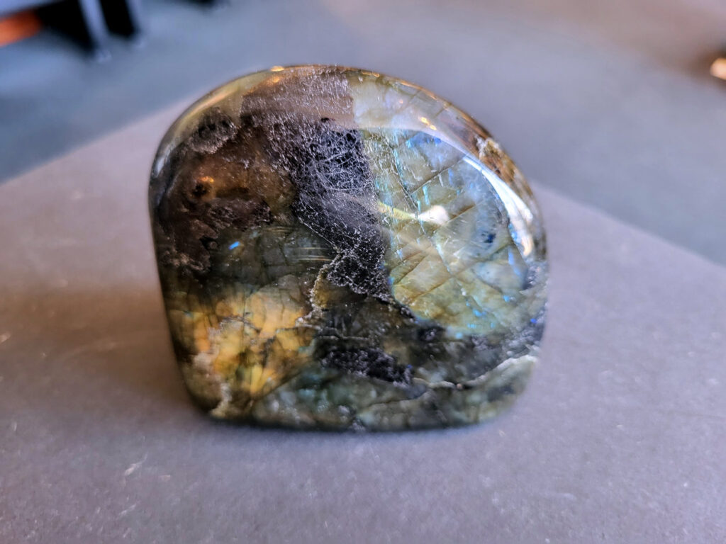 Labradoriet, 8cm hoog, 12,- euro, nr. 40

Labradoriet, beschrijving
Labradoriet is een edelsteen die bekend staat om zijn iriserende kleurenspel, ook wel labradoriseren genoemd, dat vaak doet denken aan het noorderlicht. Het is een populaire steen in de edelstenenwereld vanwege zowel zijn uiterlijk als zijn vermeende spirituele eigenschappen.
Wat is labradoriet?
Labradoriet is een veldspaatmineraal dat wordt gekenmerkt door een opaalachtig glans of iriserend effect, veroorzaakt door de lichtbreking in de interne structuur van de steen.
De meest voorkomende kleur is grijs of groenachtig grijs, maar de steen kan ook blauwe, gele, oranje, paarse of zelfs rode flitsen laten zien.
De steen is genoemd naar het Canadese schiereiland Labrador, waar het voor het eerst werd ontdekt.
Spirituele betekenis en eigenschappen:
Labradoriet wordt vaak beschouwd als een beschermende steen, vooral voor mensen die gevoelig zijn voor de energieën van hun omgeving.
Het zou helpen bij het versterken van de aura en het verminderen van energielekkage, waardoor je je weerbaarder voelt.
Labradoriet wordt geassocieerd met het versterken van intuïtie, het vergroten van het bewustzijn en het transformeren van negatieve energieën.
Het wordt ook gebruikt om blokkades op te heffen en de innerlijke wijsheid te onthullen.
Gebruik:
Labradoriet wordt vaak verwerkt in sieraden zoals hangers, armbanden en oorbellen.
Het kan ook als ruwe steen, knuffelsteen of in andere vormen worden gebruikt, bijvoorbeeld in een huis of op een werkplek.
Labradoriet kan worden gereinigd door het onder stromend water te houden of door het te reinigen met een andere steen zoals bergkristal of seleniet.
Vindplaatsen:
Labradoriet wordt gevonden op verschillende locaties over de hele wereld, waaronder Canada, Finland, Madagaskar en Rusland.
-Kunstgalerie Arnold-